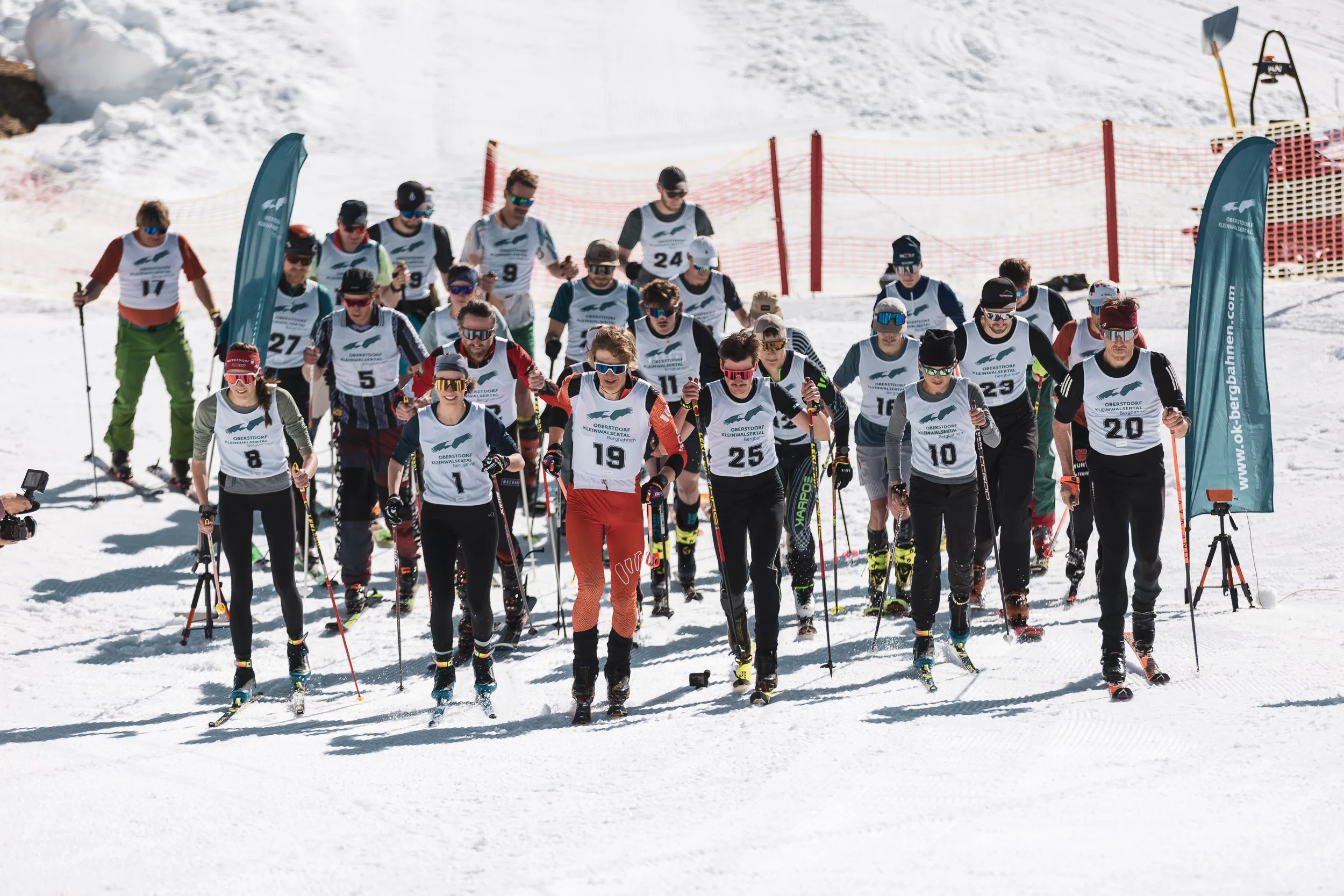 Startaufstellung der Skimo-Läufer mit Startnummern vor dem Massenstart, dahinter die Allgäuer Alpen