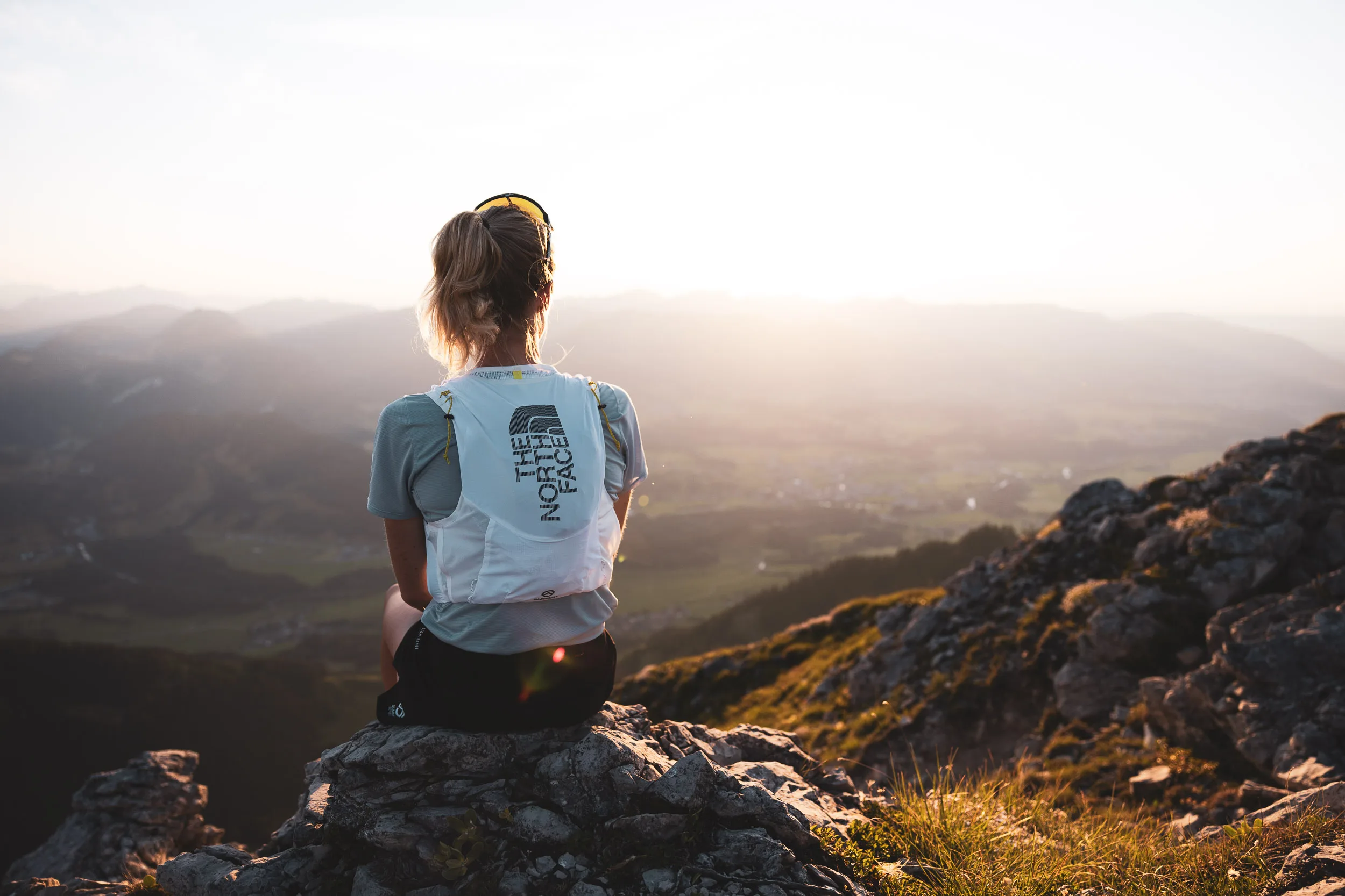 Ronja Morell sitzt auf einem Felsen und blickt in die tief stehende Abendsonne