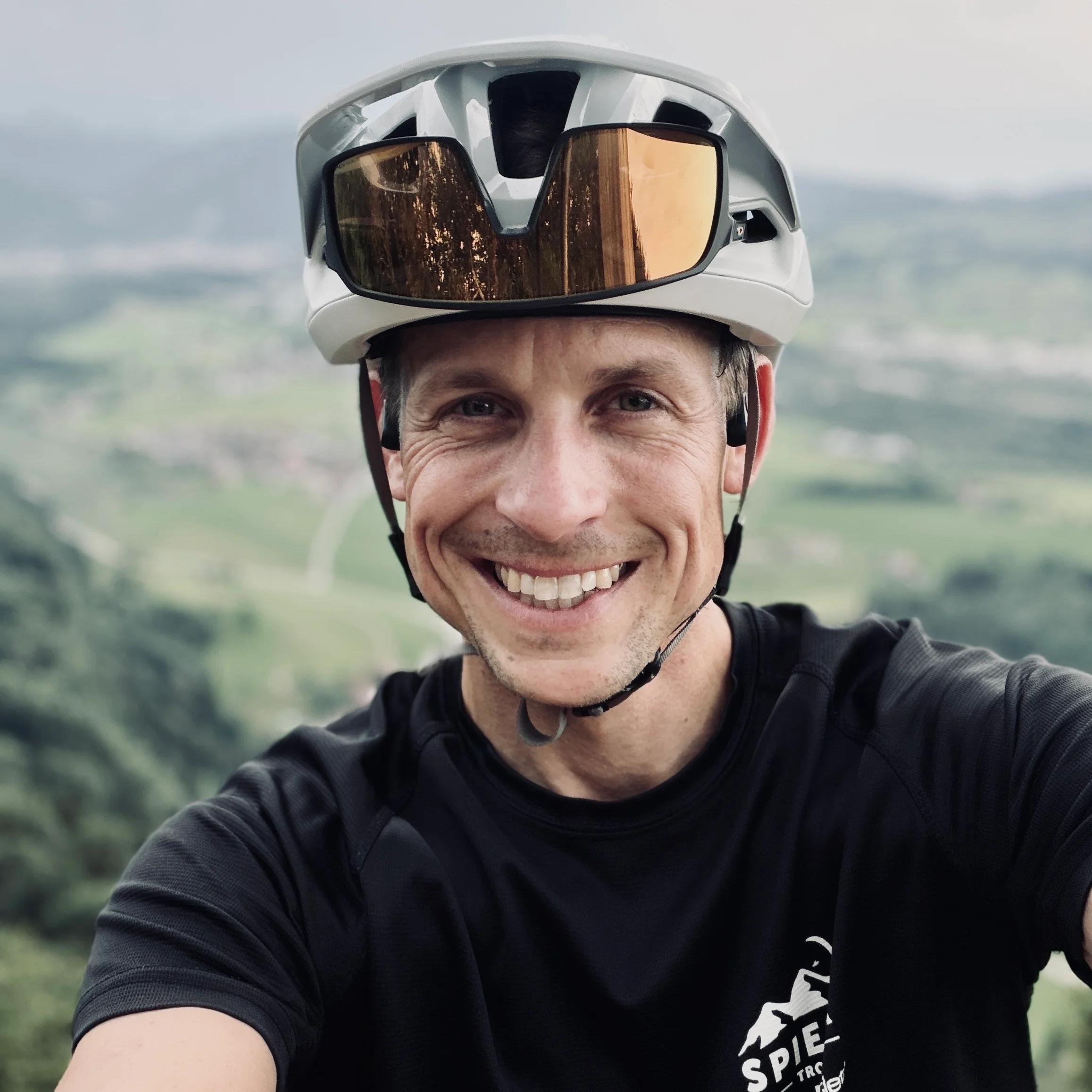 Bastian Morell lächelt mit Fahrradhelm und hochgesteckter Sonnenbrille in die Kamera.