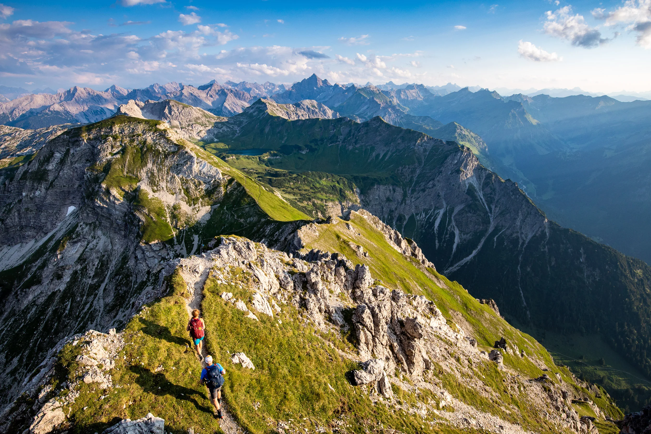 Caroline Nantke und Harald Dreyer wandern auf einem Grat dem warmen Abendlicht entgegen