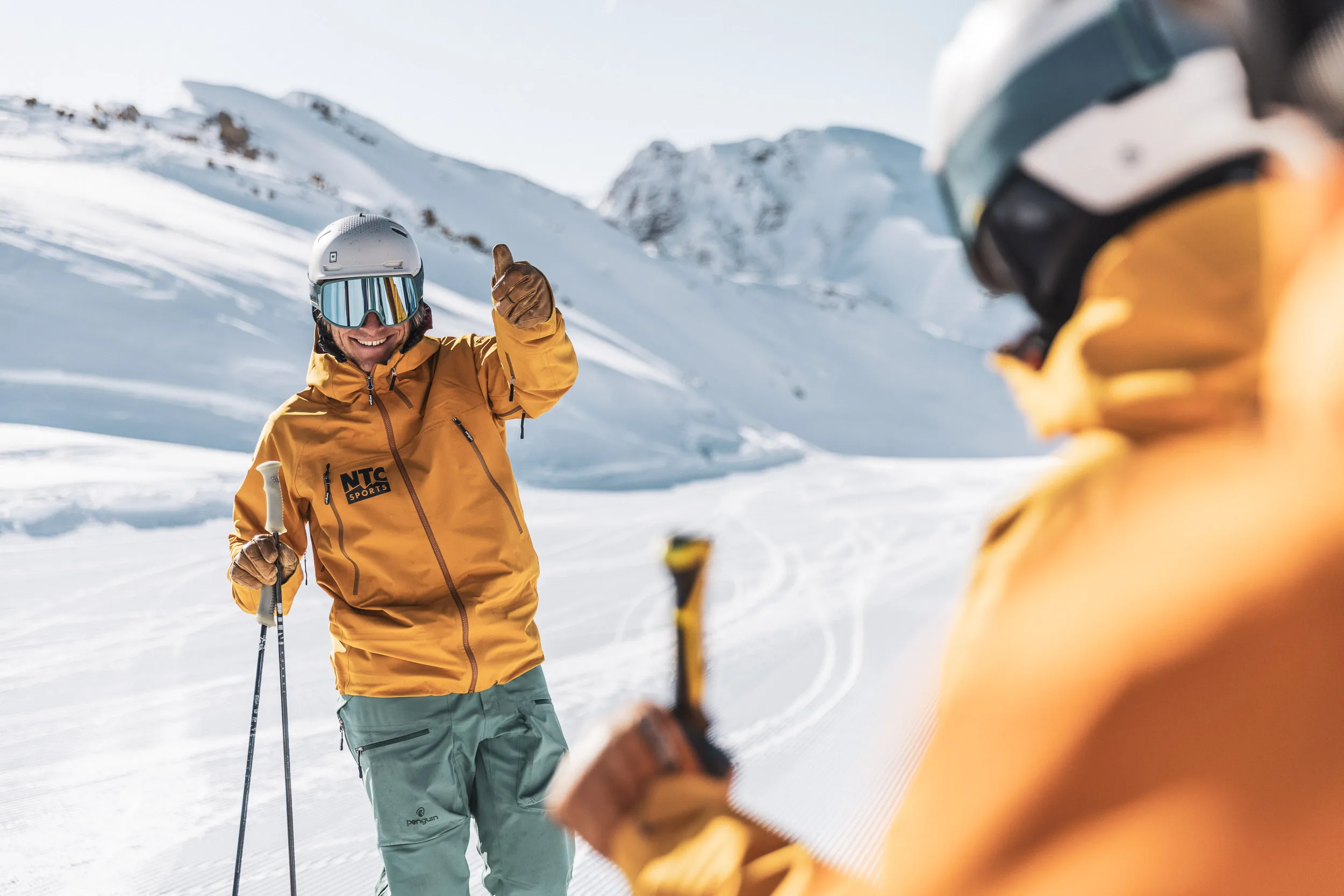 Skilehrer zeigt einer Gruppe mit der Hand die Fahrtrichtung