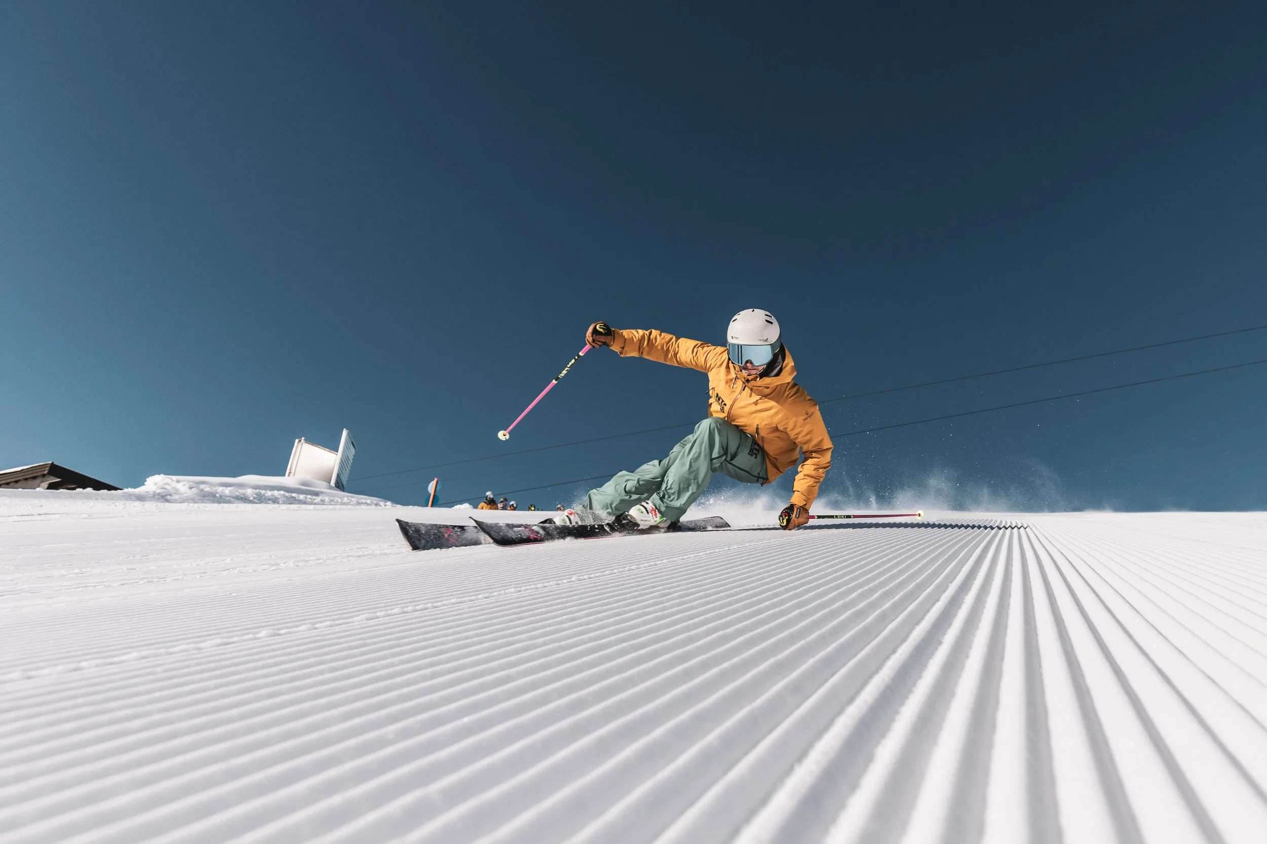 Skilehrer legt sich auf frisch präparierter Piste in eine tiefe Kurve