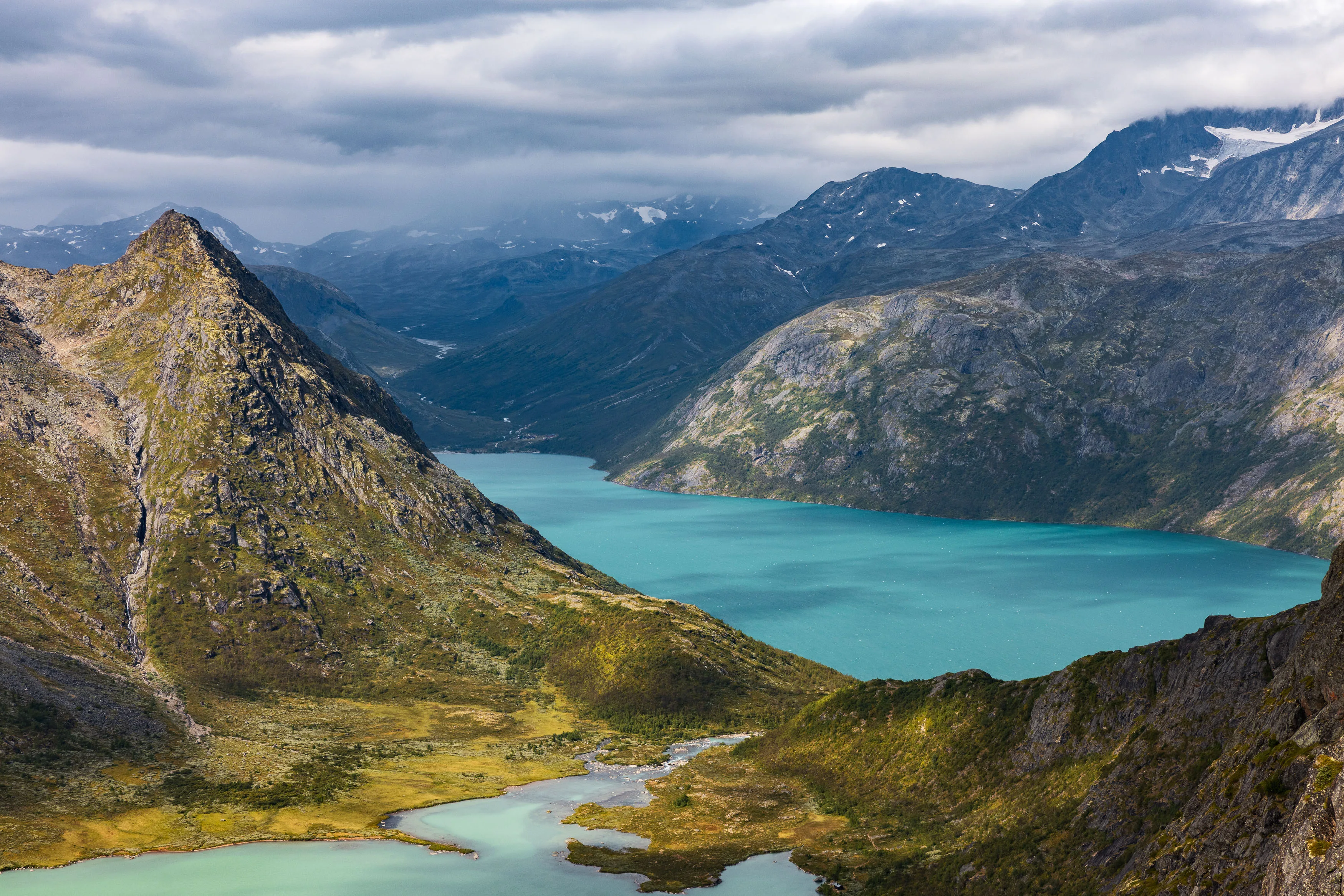 Türkisfarbener Bergsee liegt zwischen schroffen Graten und dunklen Berghängen