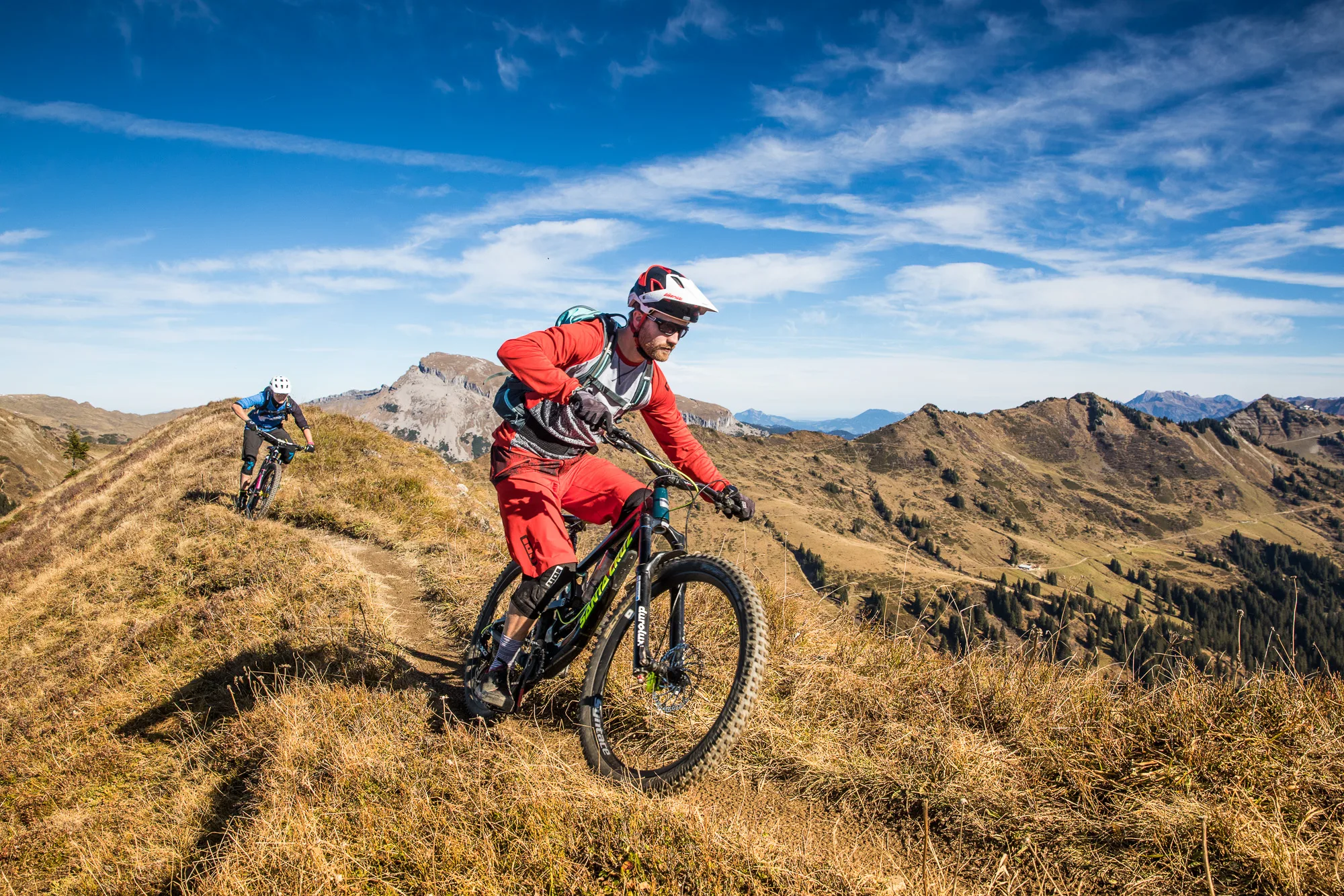 Enduro-Mountainbiker fährt im roten Outfit über einen trockenen Trail oberhalb des Kleinwalsertals