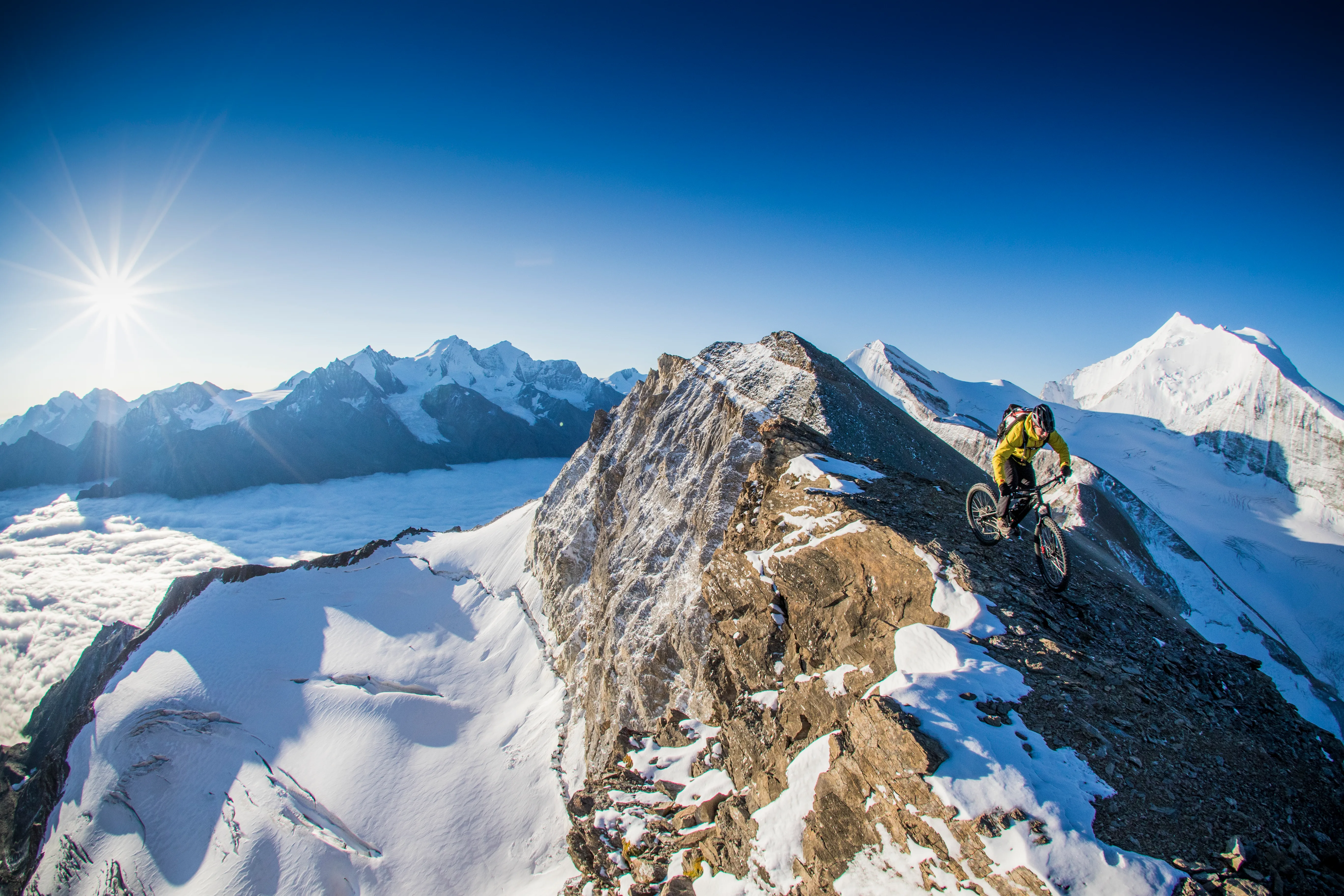 Florian Häusler fährt mit dem Mountainbike entlang eines schneebedeckten Kamms im Wallis.