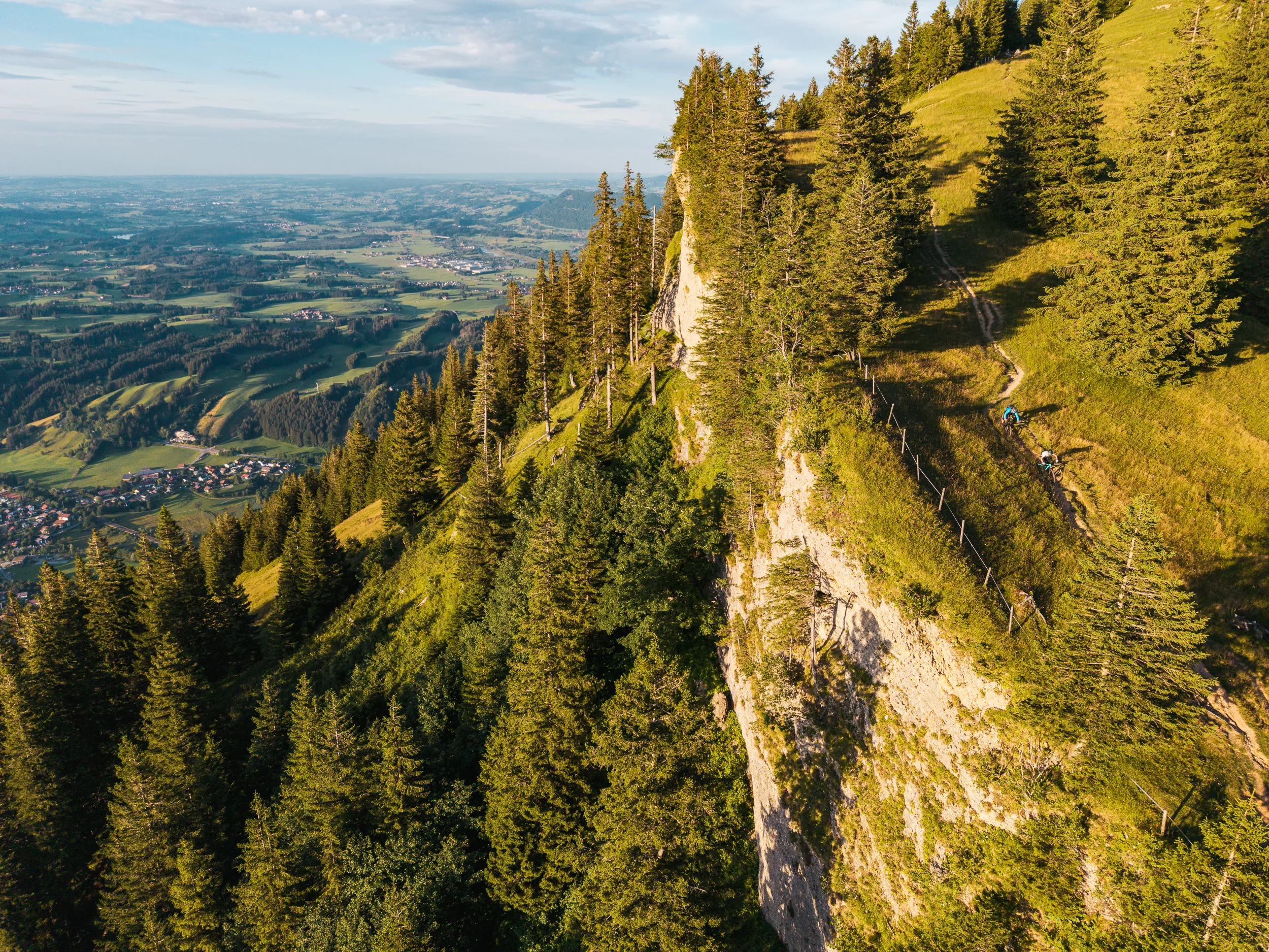 Zwei Mountainbiker folgen einem ausgesetzten Bergtrail entlang einer Felskante