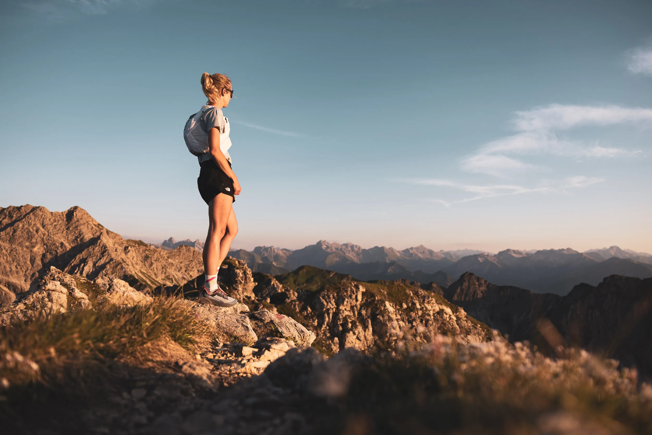 Ronja Morell steht auf einem Berggrat und blickt über die Allgäuer Alpen