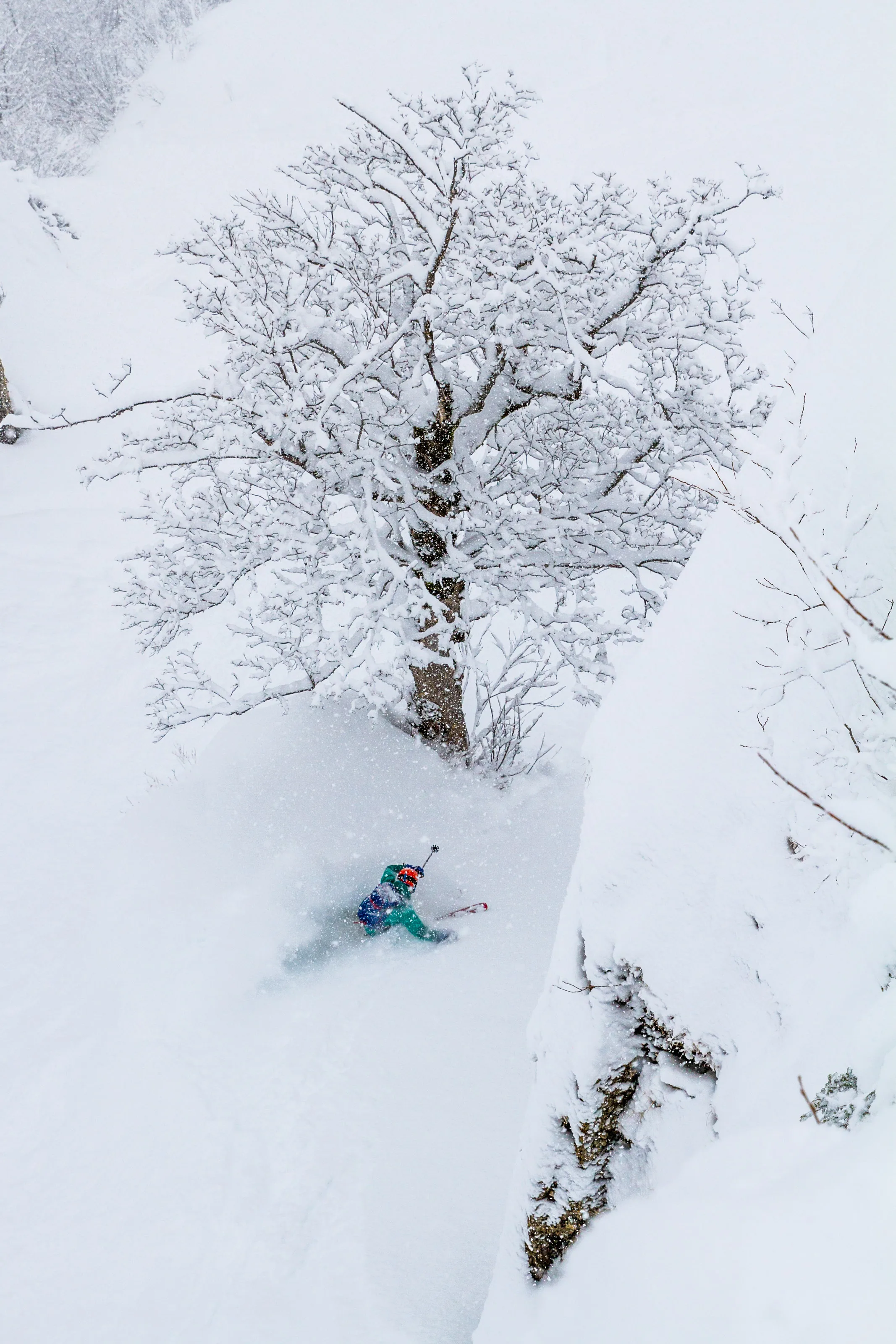 Freerider fährt in einer steilen Schneerinne unmittelbar neben einer Felswand