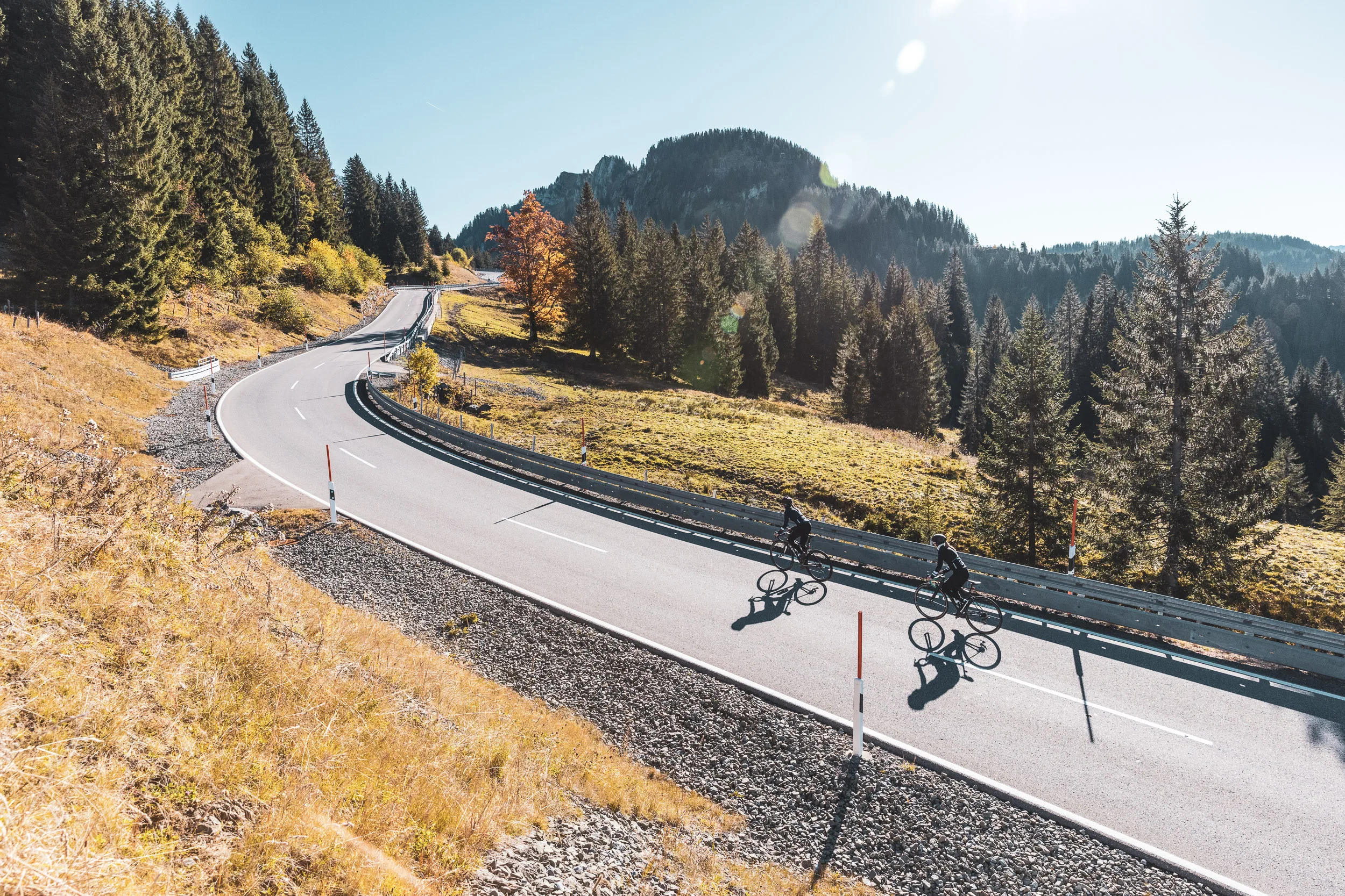 Luftaufnahme von zwei Rennradfahrerinnen auf einer weiten Passkurve