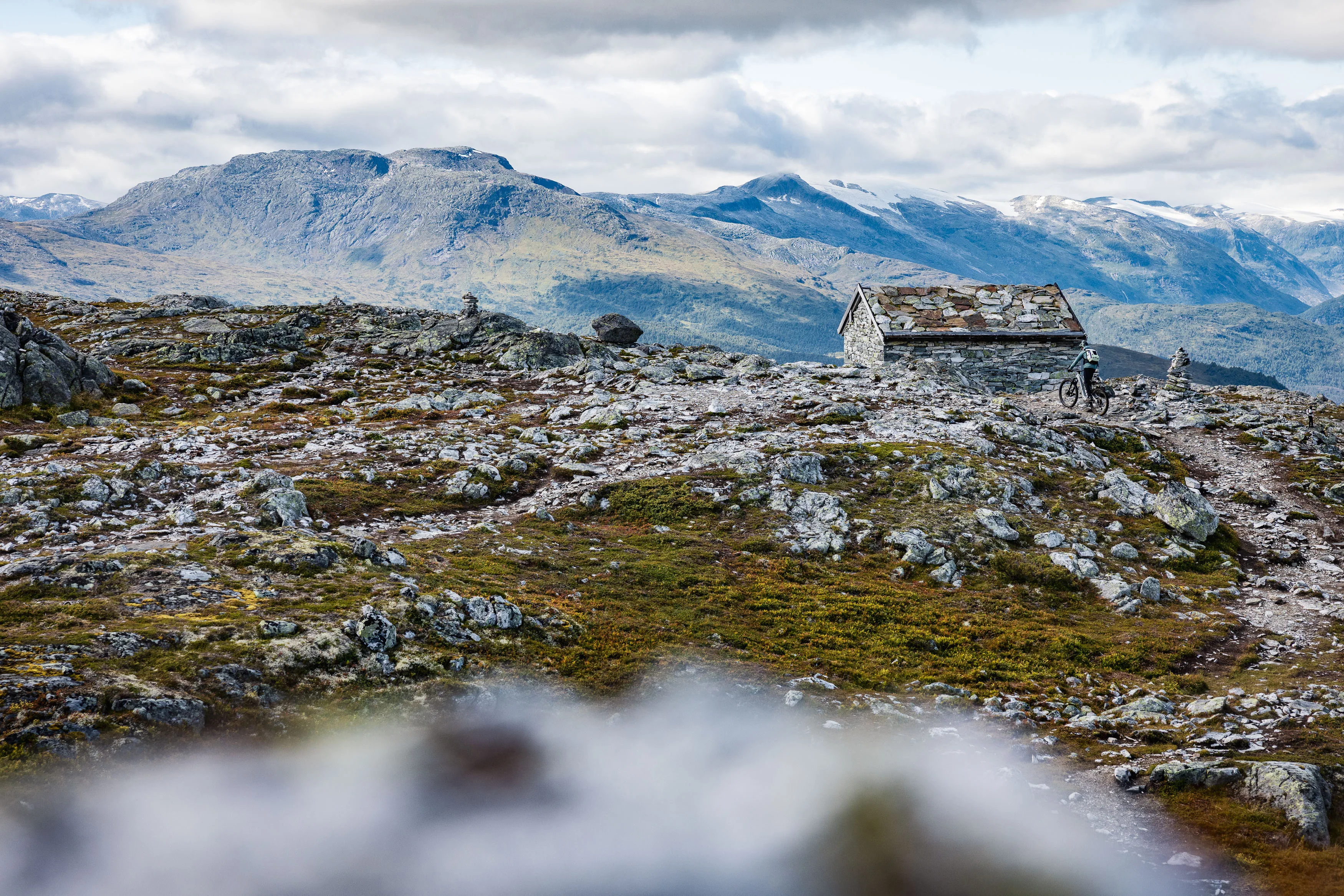 Verwitterte Holzhütte steht allein auf einer steinigen Hochebene vor fernen Bergen