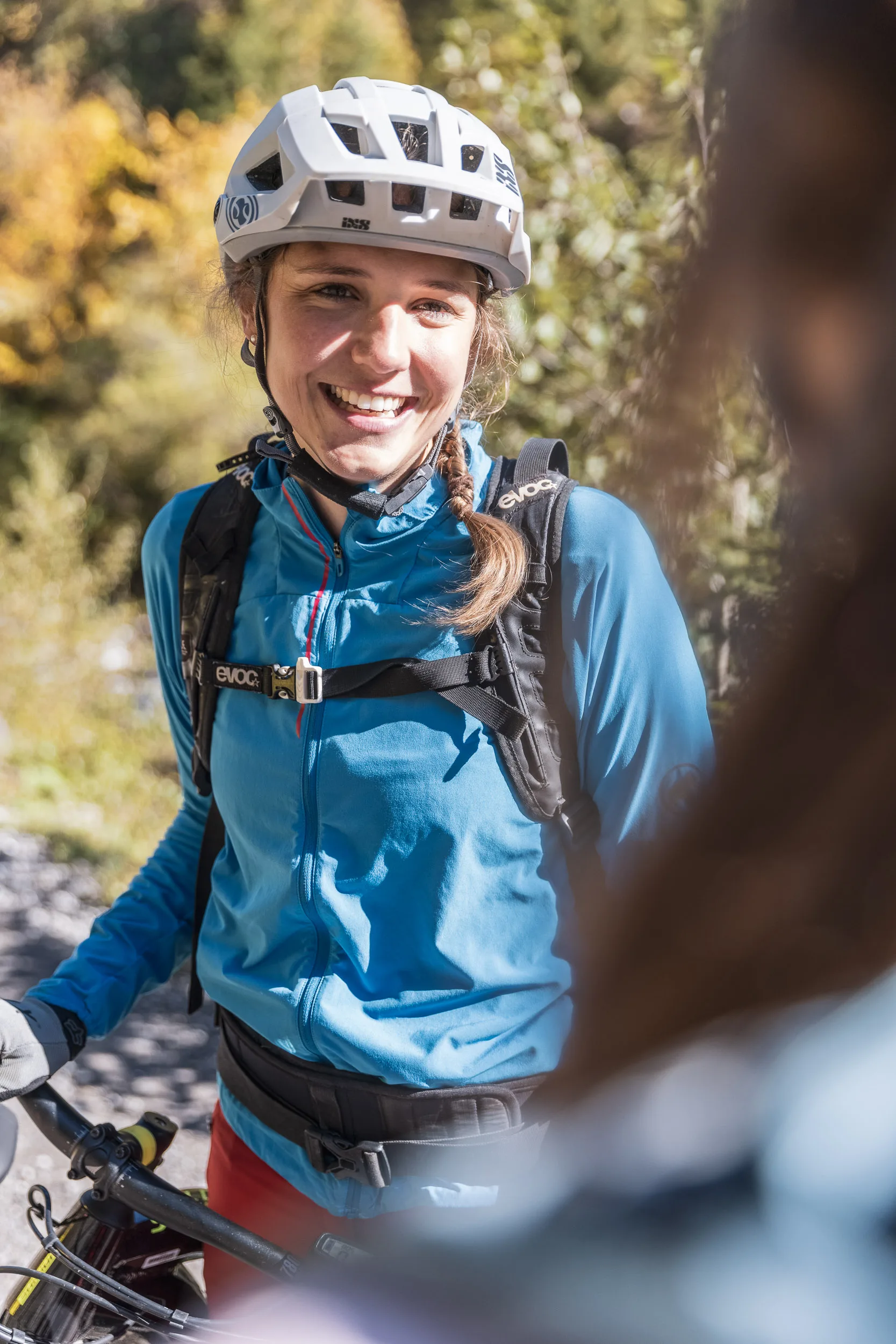 Andrea Geiger steht mit Mountainbike auf einem Bergweg im Herbstlicht