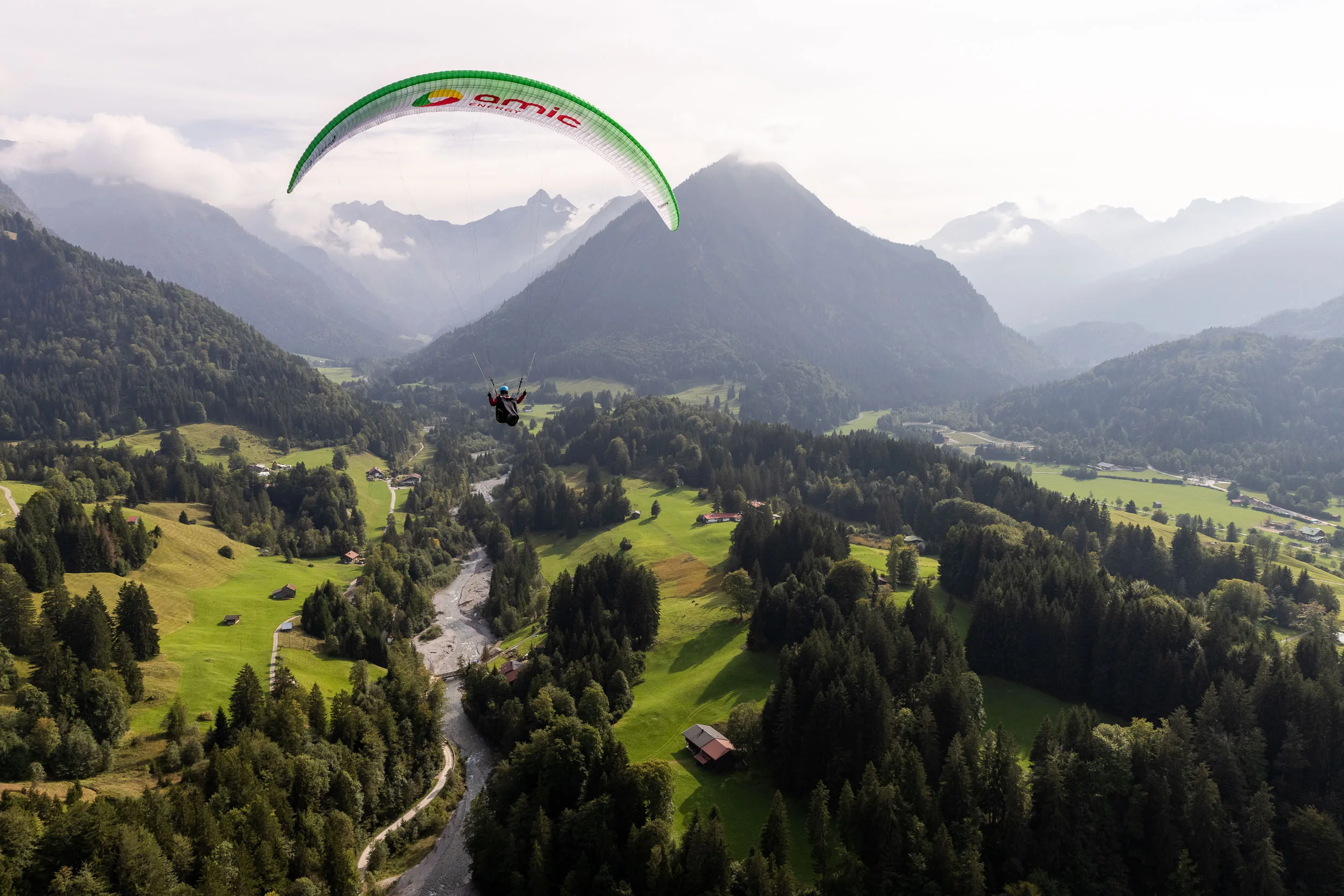 Klaudia Bulgakow fliegt mit ihrem Gleitschirm über dem grünen Tal bei Oberstdorf.