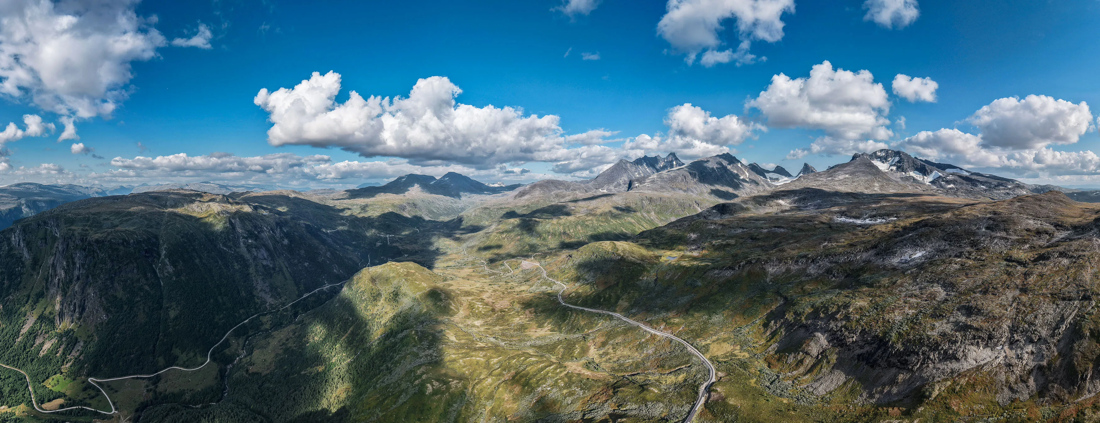 Weites Luftpanorama einer felsigen norwegischen Berglandschaft unter sommerlichen Wolken