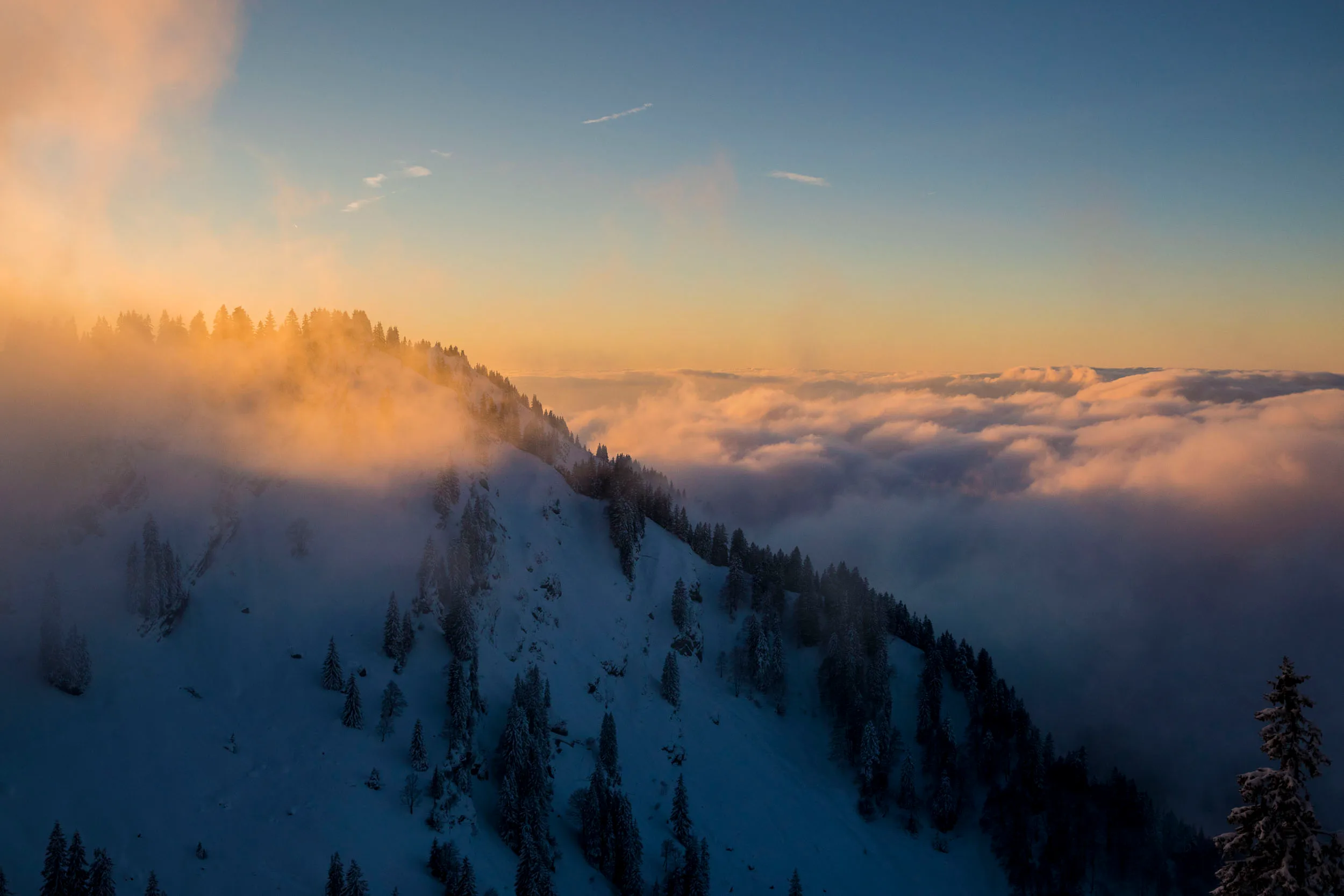 Wolken ziehen über die verschneite Nagelfluhkette im Abendlicht.