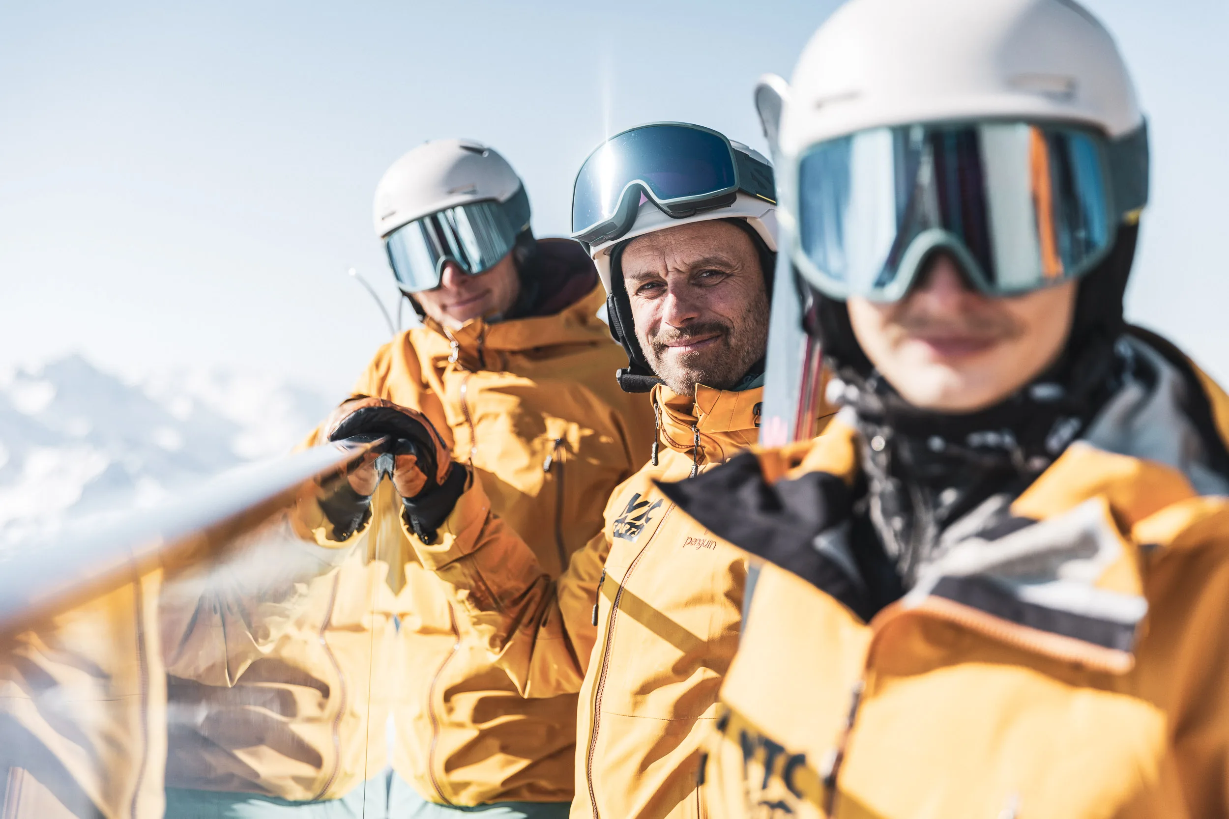 Drei Skilehrer stehen dicht beieinander an einer Liftstation