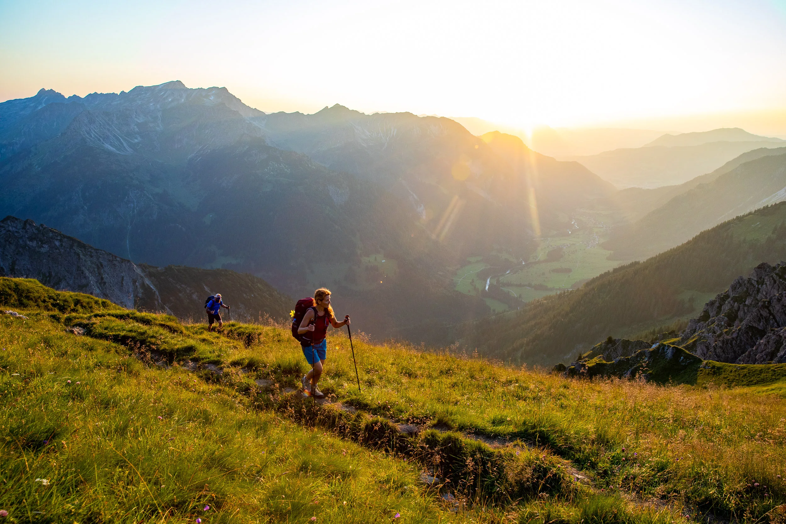 Caroline Nantke steigt auf einem Wiesenpfad dem tiefen Sonnenlicht entgegen