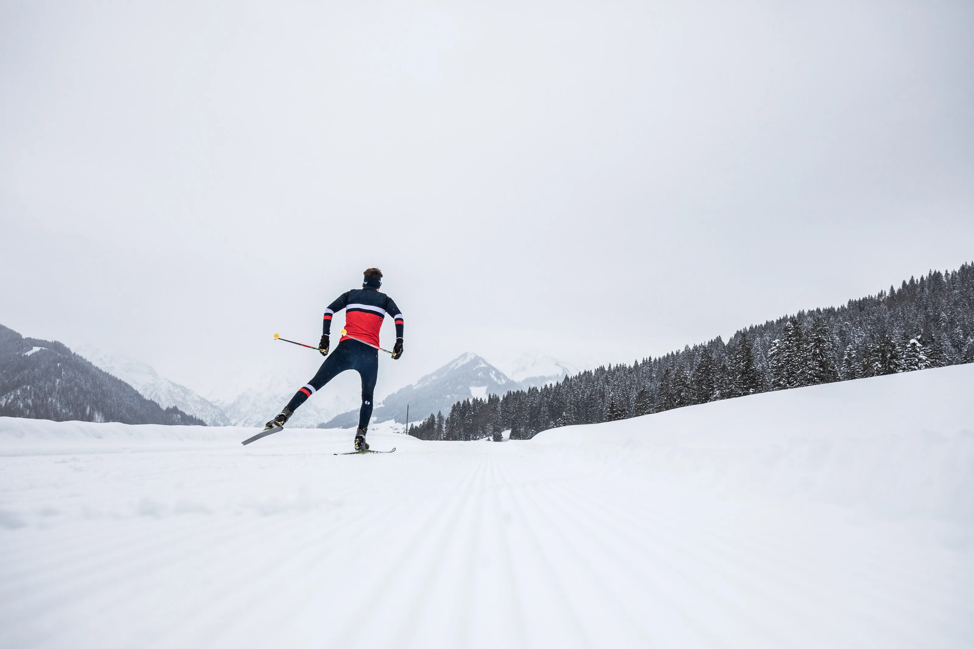 Nahes Porträt von Michael Schnetzer beim Skating-Langlauf vor verschneiten Bergen.