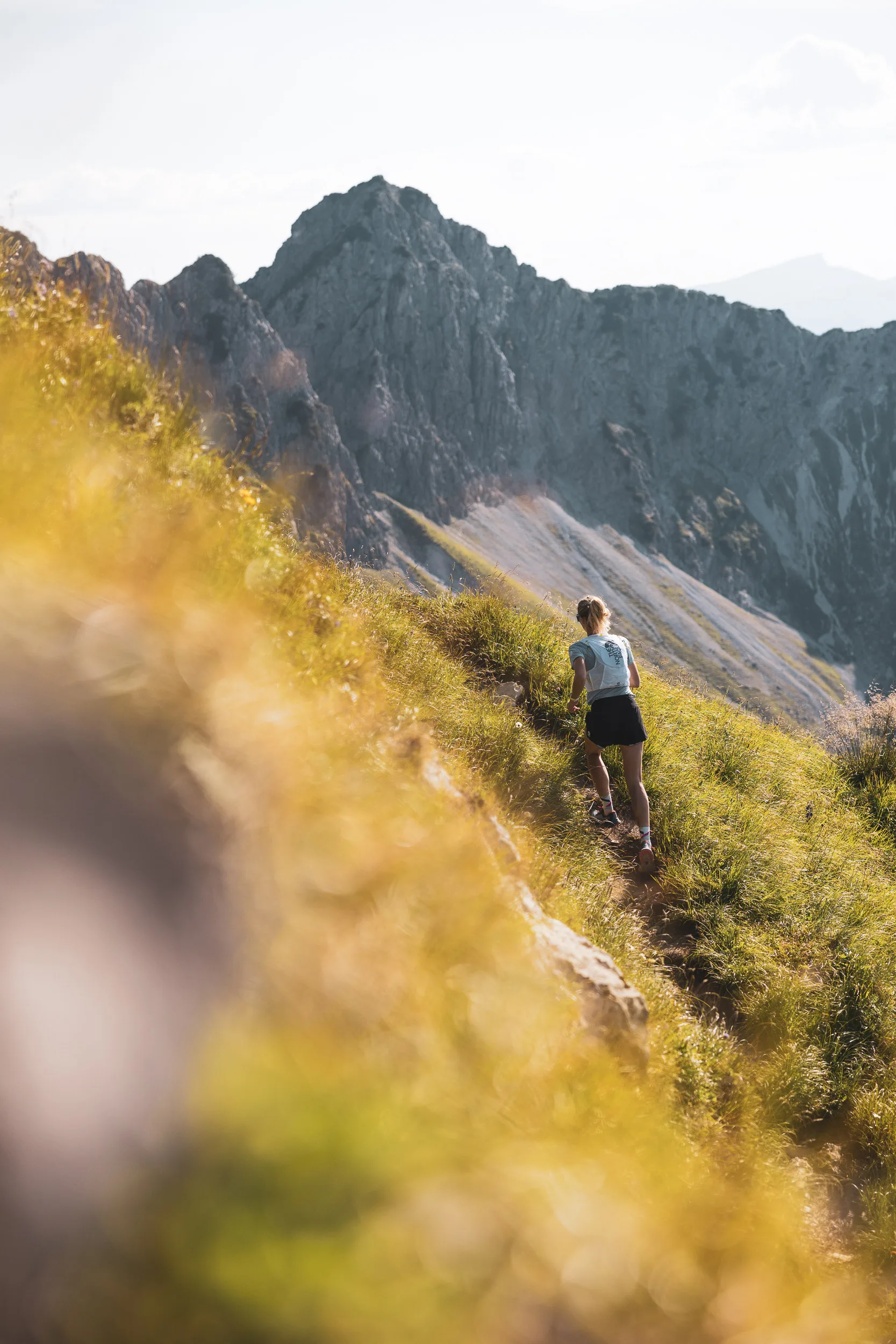 Ronja Morell läuft auf einem schmalen Bergpfad vor einer felsigen Bergkette