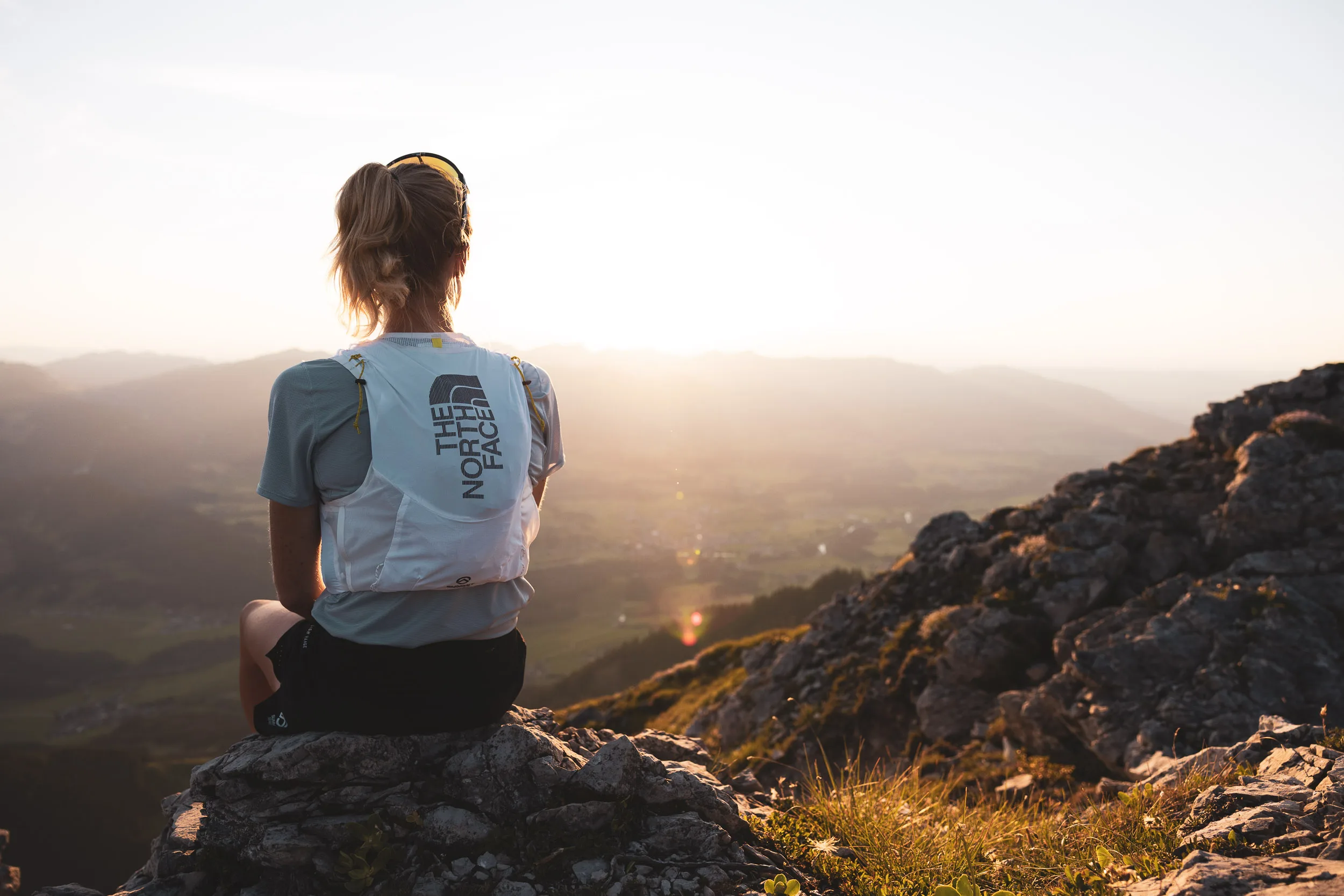 Ronja Morell sitzt auf einem Felsen mit Blick in die tief stehende Sonne