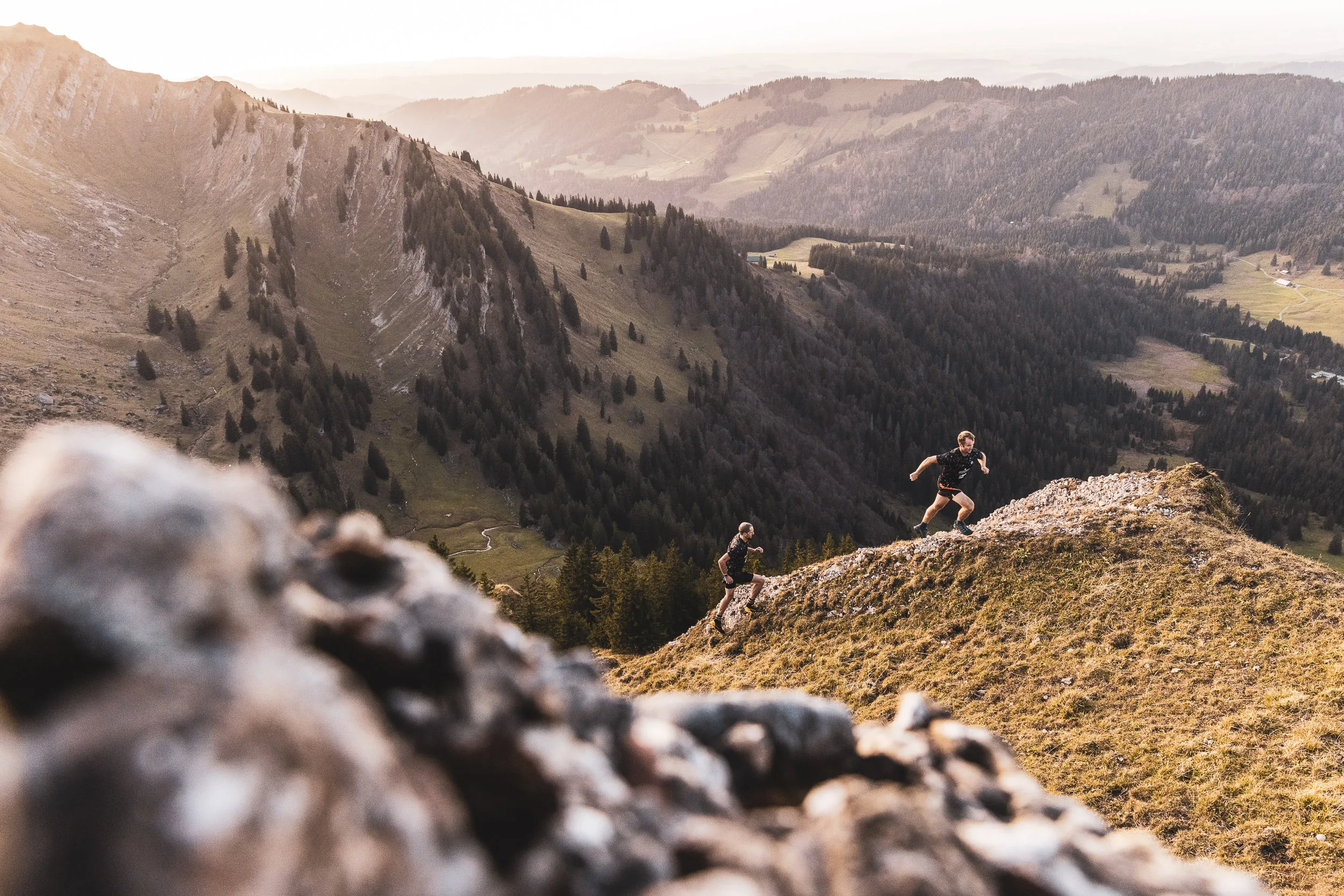 Trailrunner bewegen sich ueber einen Bergpfad mit weitem Blick ins Allgaeu
