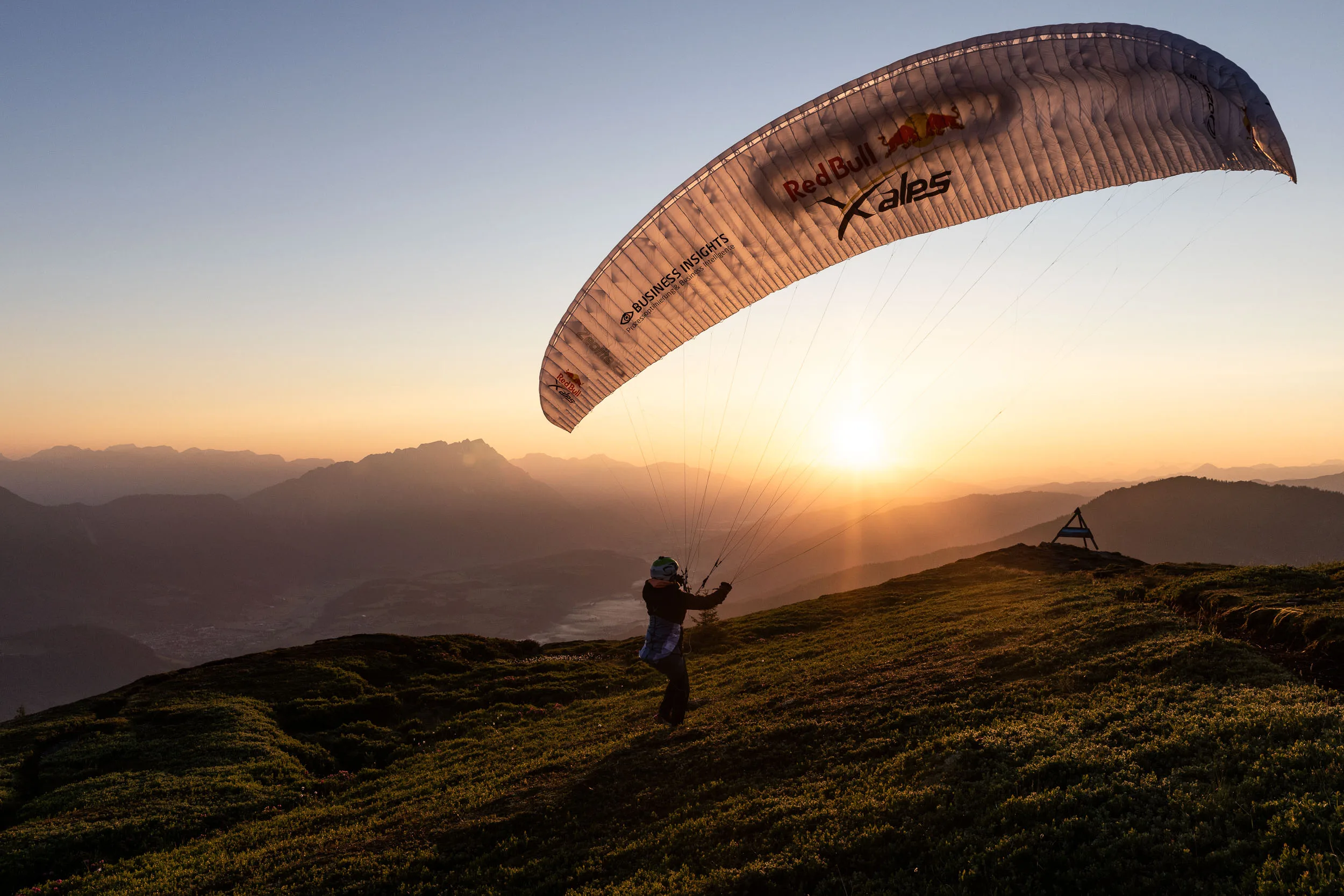 Gleitschirmpilotin bereitet den Start vor der aufgehenden Sonne im Ennstal vor