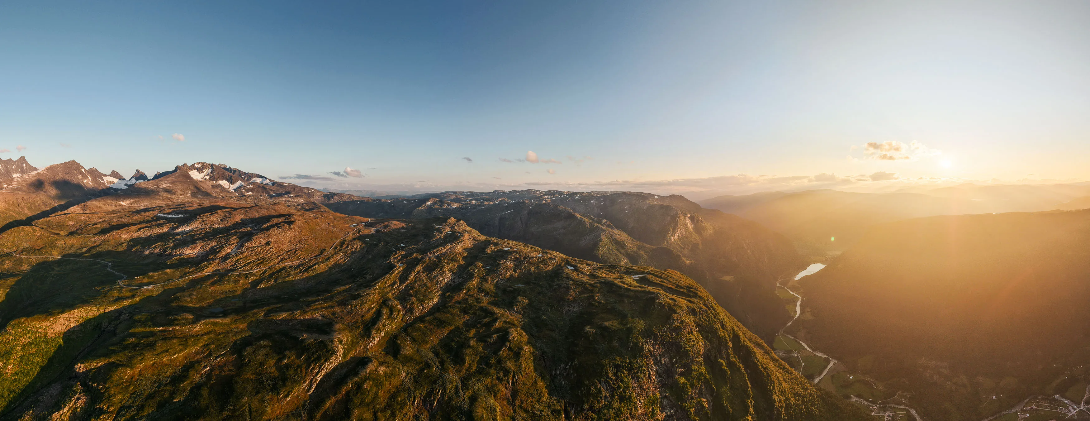 Tiefe Abendsonne fällt über felsige Bergrücken und einen See im Tal