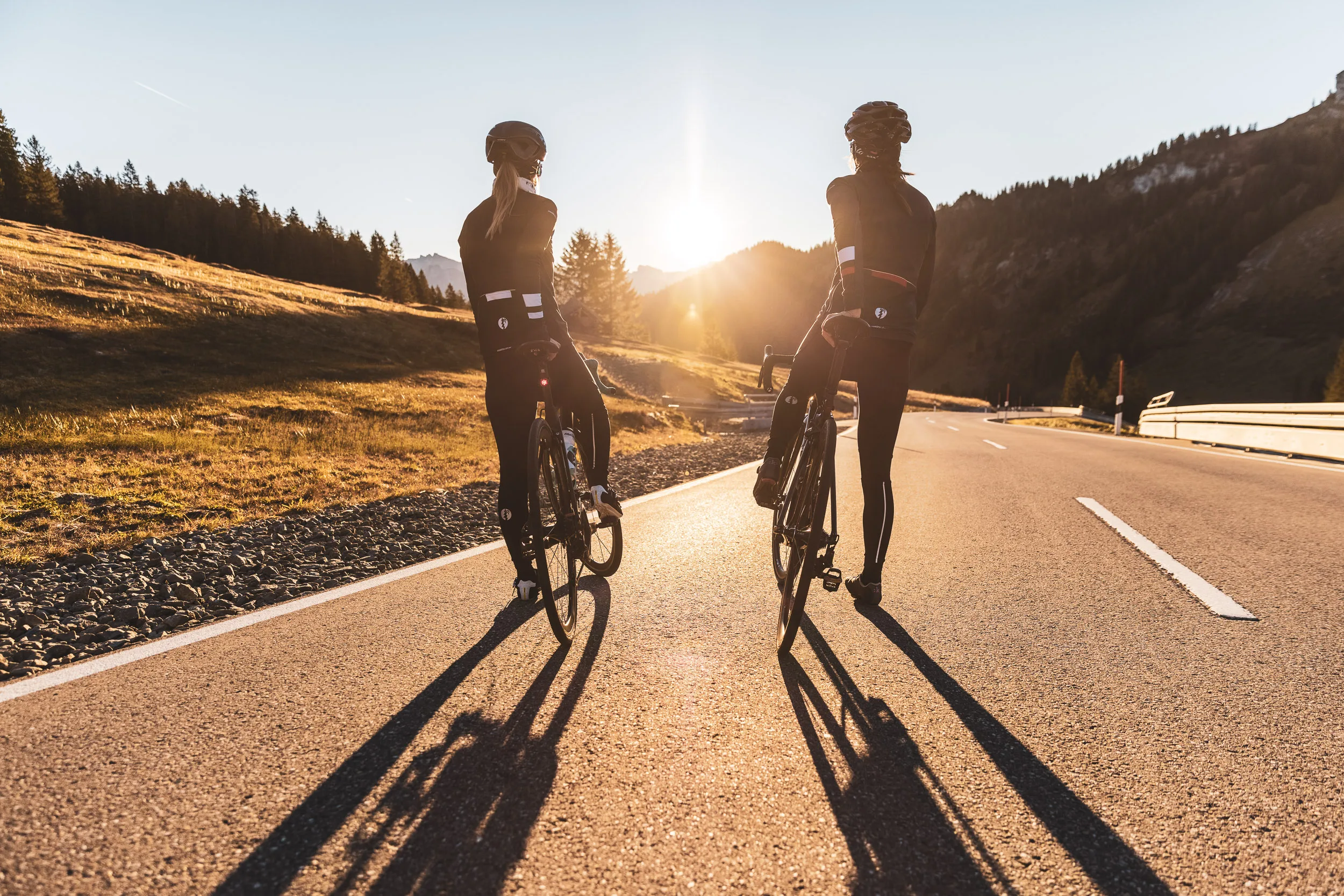Zwei Rennradfahrerinnen halten mit ihren Rädern auf der Passstraße
