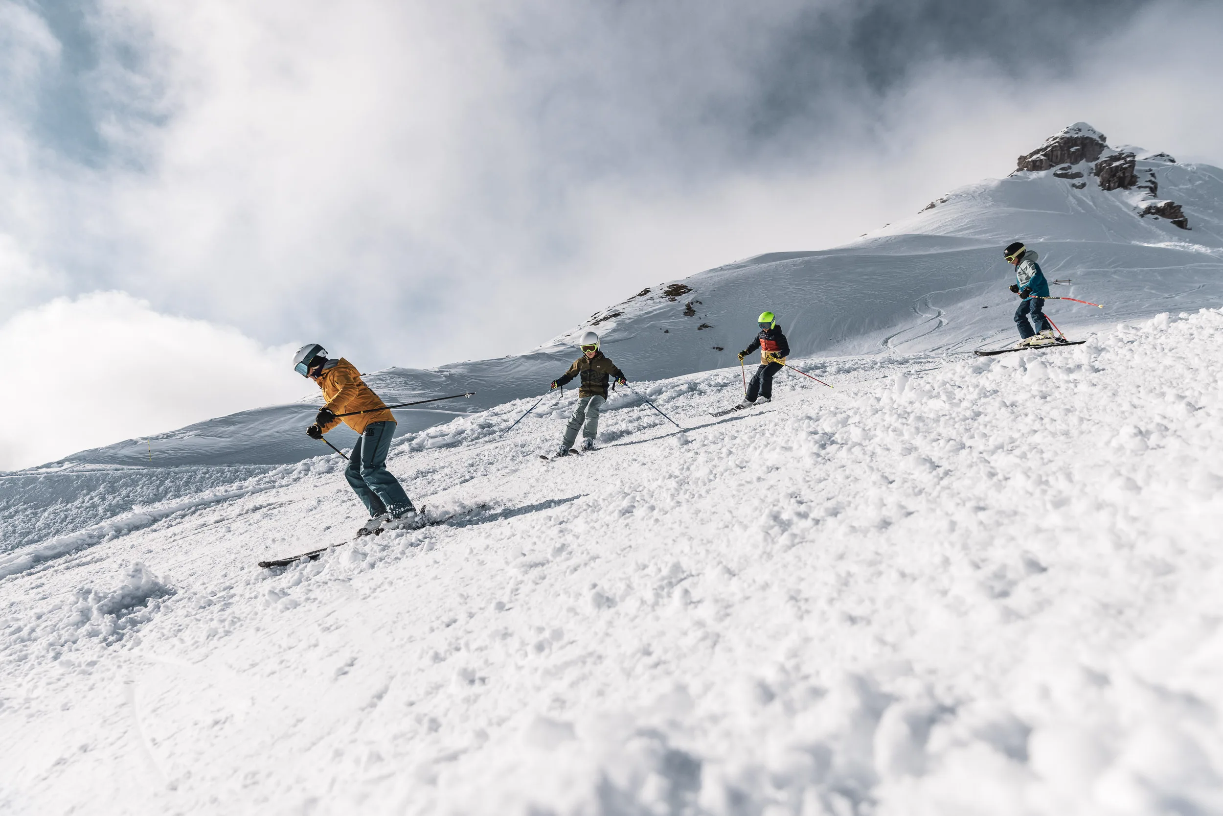 Skilehrer führt eine Gruppe über einen offenen Schneehang