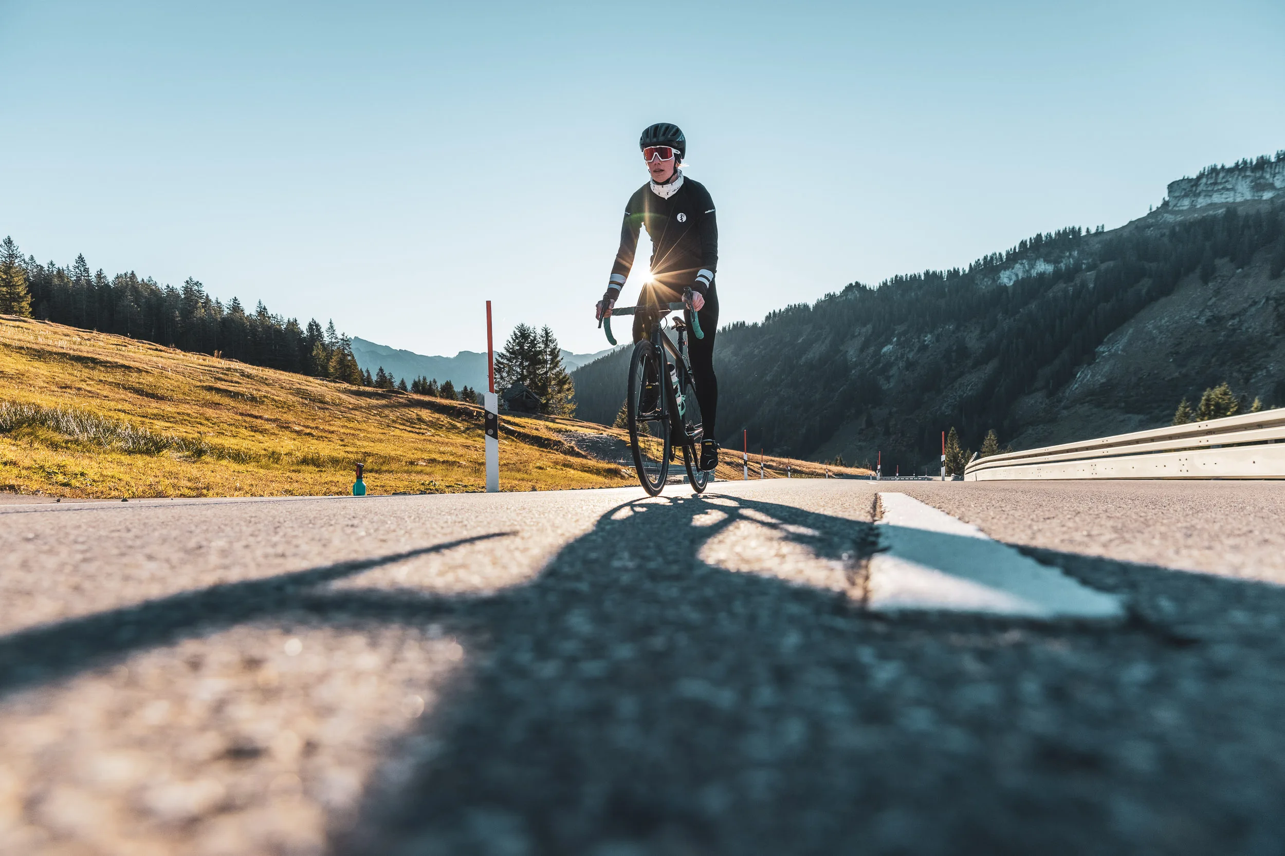 Rennradfahrerin fährt auf einer stillen Passstraße im Herbst
