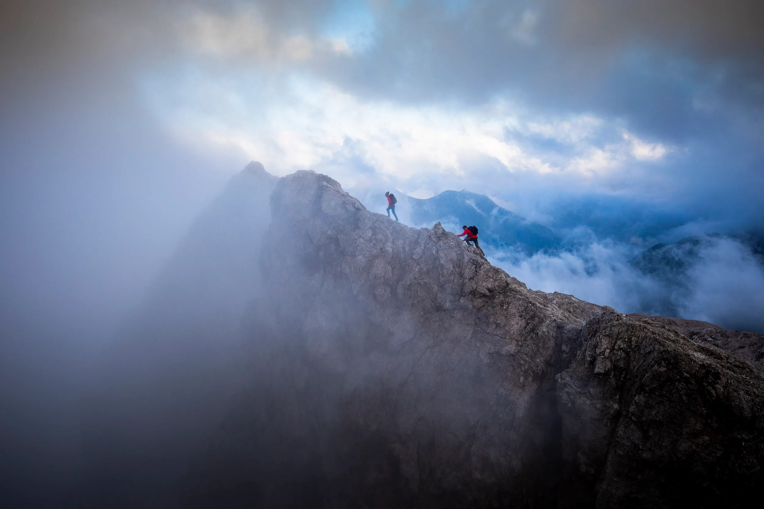 Raphaela Haug und Tom Besser stehen auf einem Felsgrat zwischen aufziehenden Wolken
