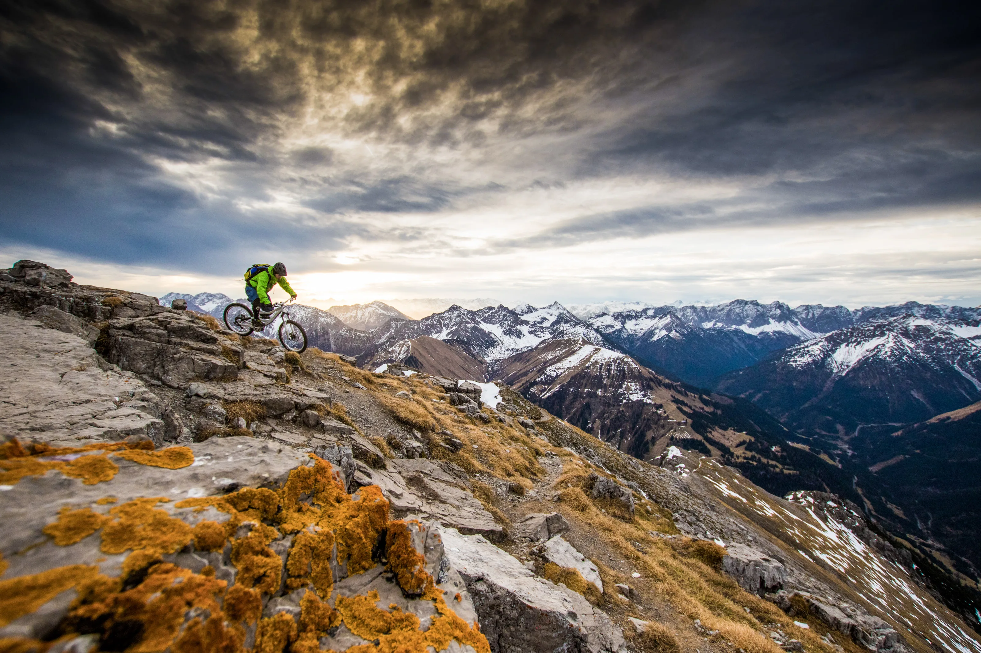 Florian Bergmann fährt mit dem Mountainbike über einen felsigen Trail vor dem Panorama der Lechtaler Alpen.