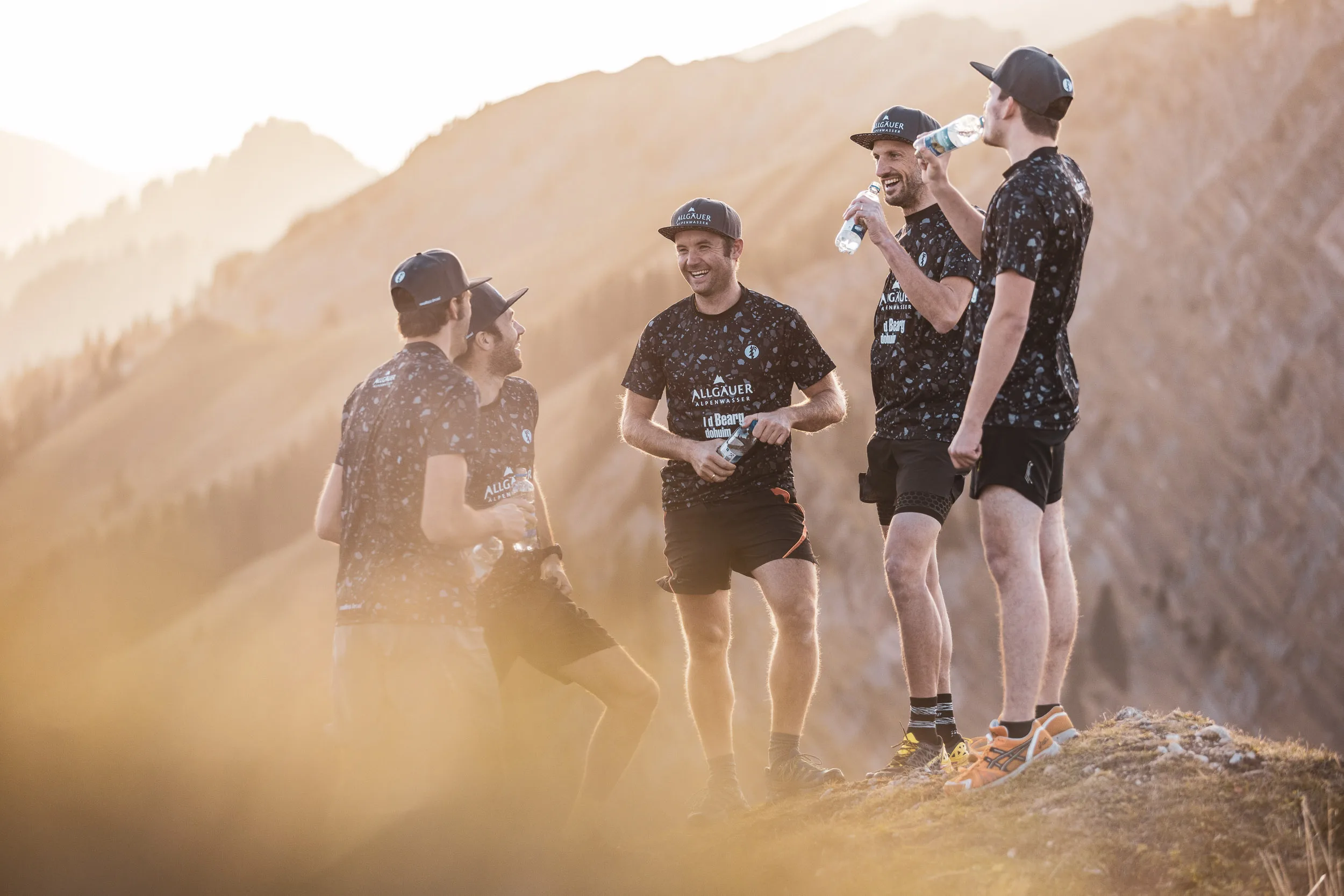 Laufteam in staubigem Abendlicht auf einem Berggrat der Nagelfluhkette