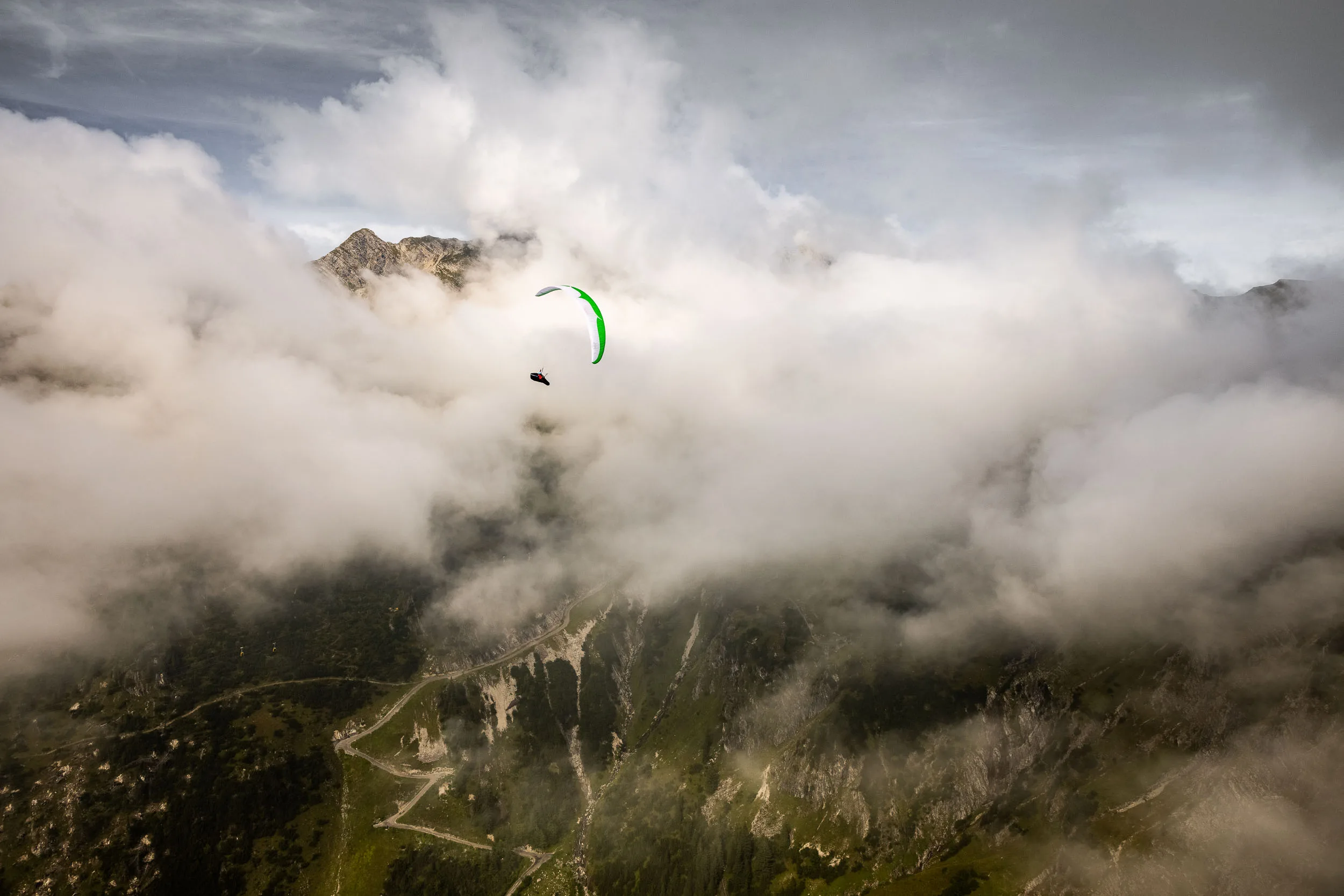 Klaudia Bulgakow fliegt mit ihrem Gleitschirm über den wolkigen Hängen des Nebelhorns.