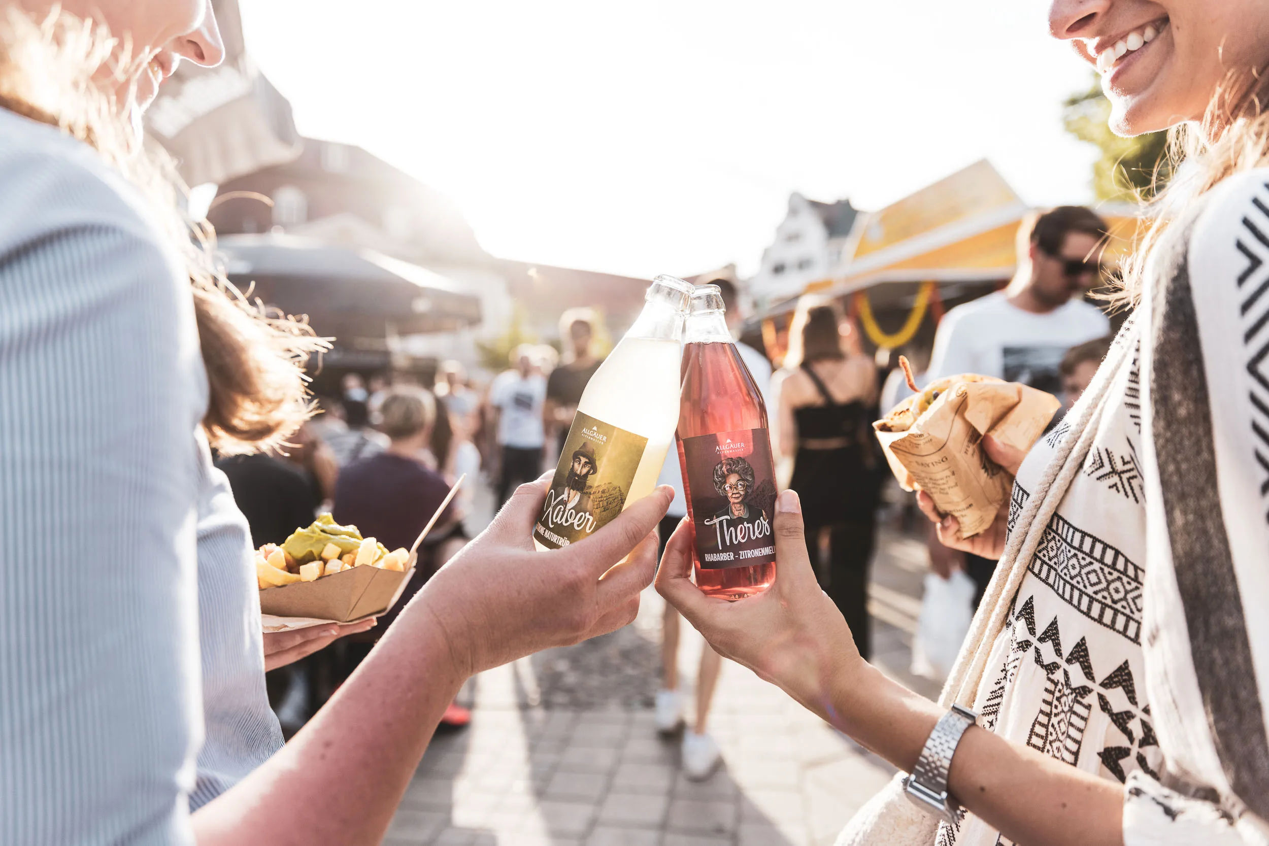 Besucherinnen stossen mit Flaschen auf dem Street Food Markt an.