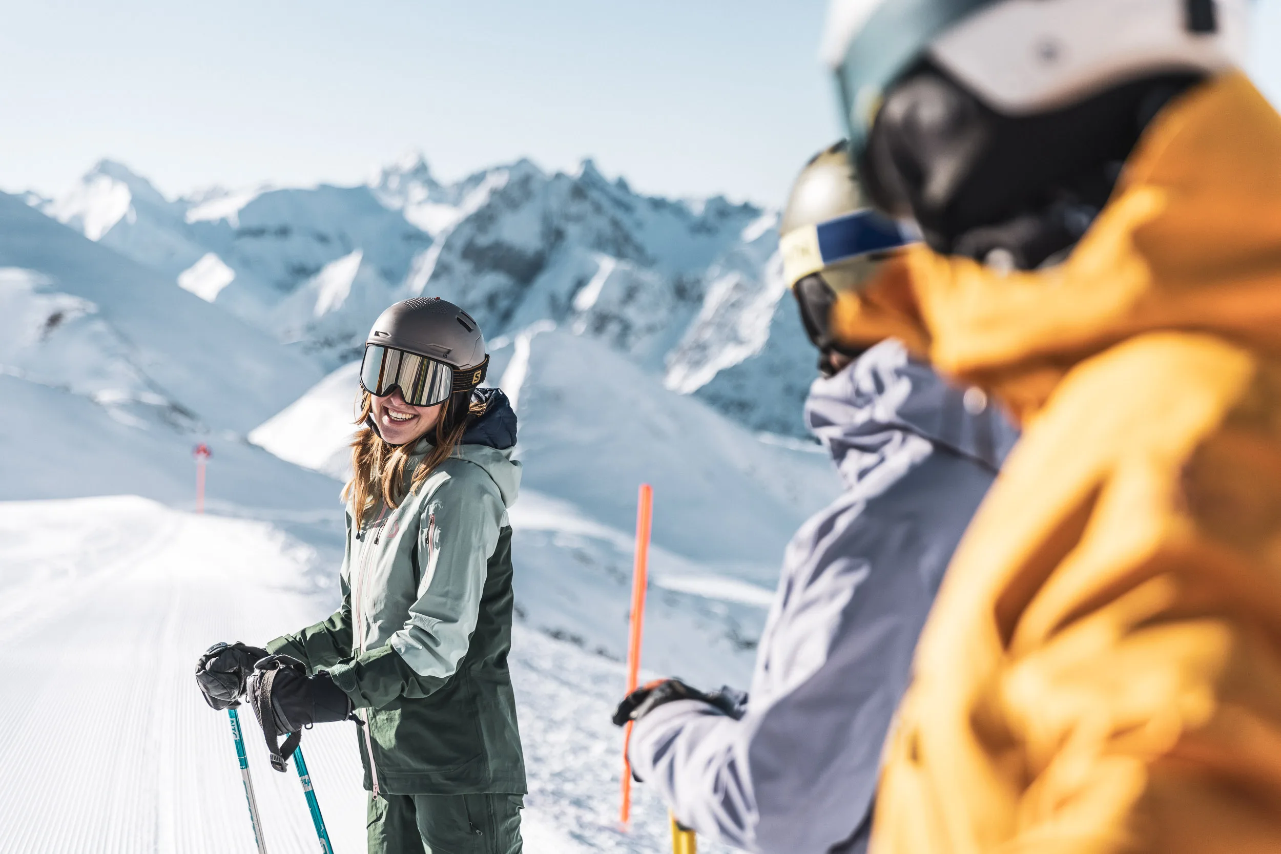 Skifahrerin hört einer Erklärung auf der Piste zu, Lehrkräfte unscharf im Vordergrund