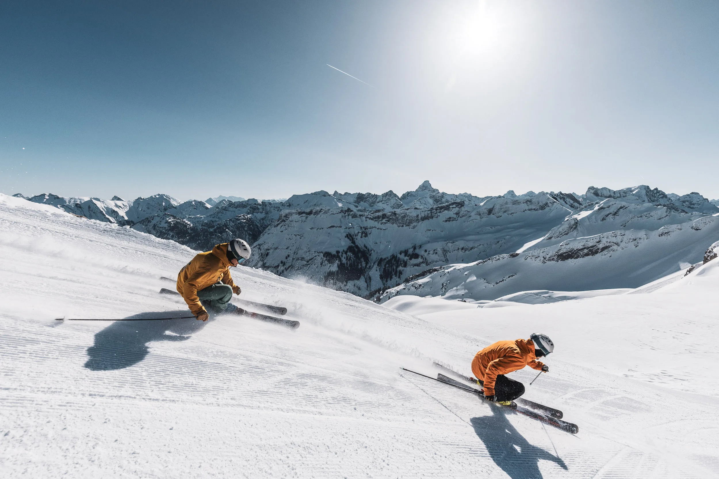 Zwei Skilehrer fahren parallel in tiefen Kurven über den Schneehang
