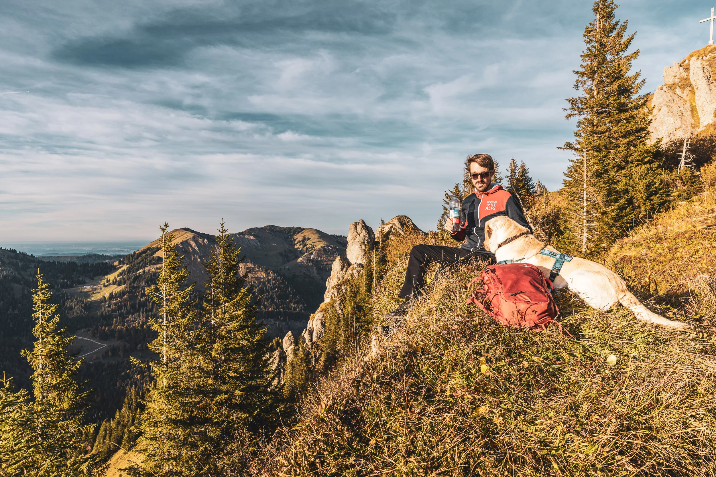Andreas Kögel und Oskar rasten gemeinsam auf einer Bergwiese mit Blick über das Allgäu