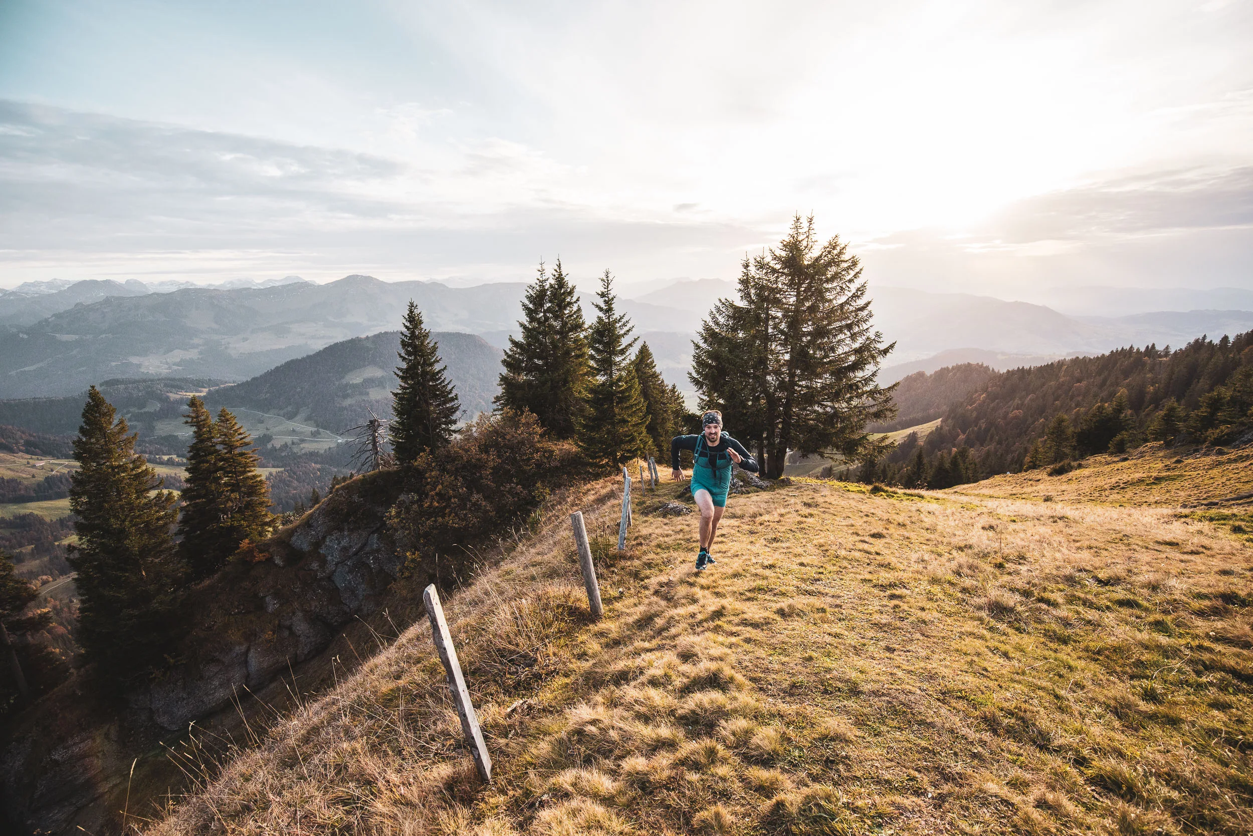 Andreas Kögel läuft an Zaunpfosten vorbei einen sonnigen Bergpfad hinauf.