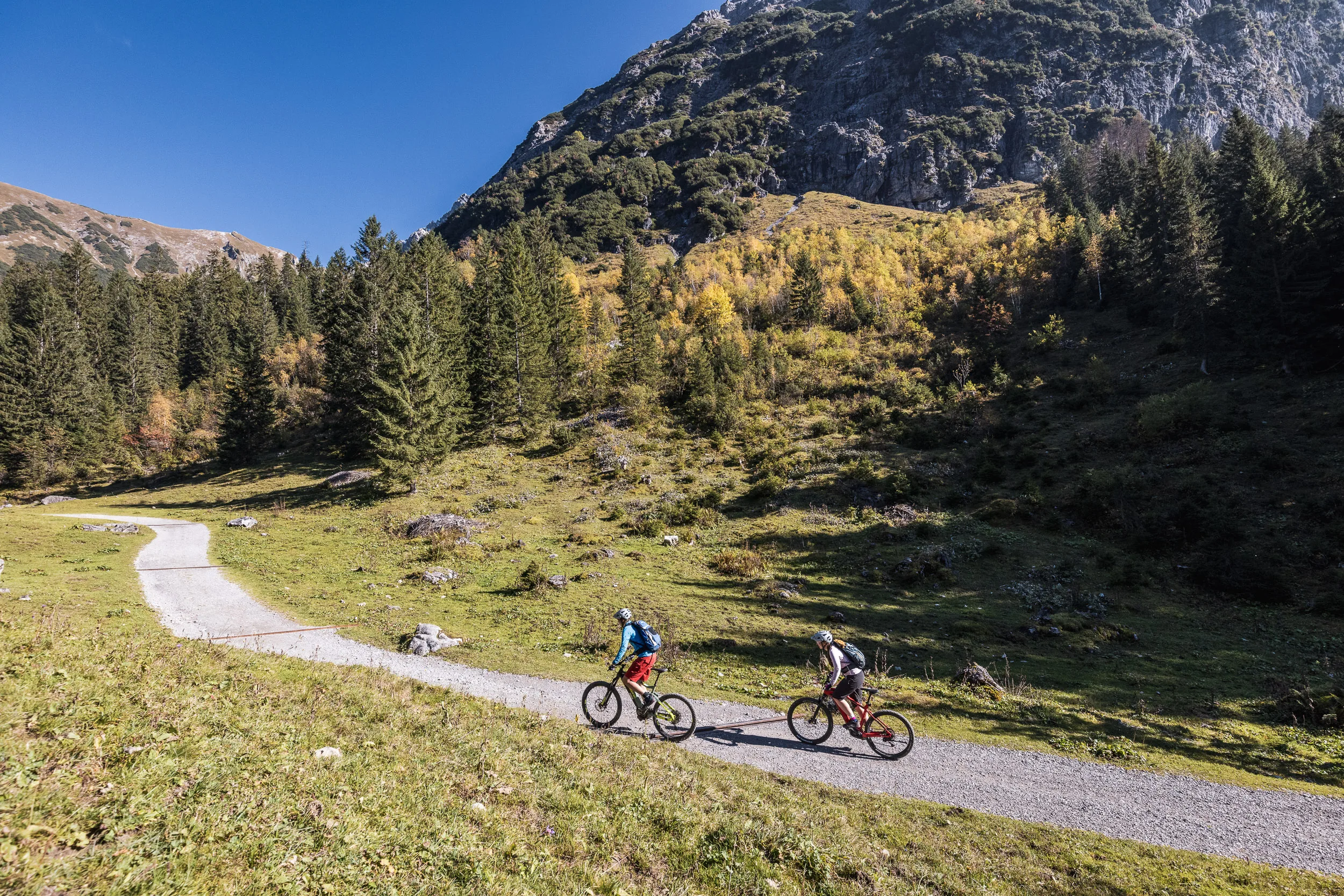 Silvi Vogel und Andrea Geiger fahren mit Mountainbikes durch herbstliche Bergwiesen