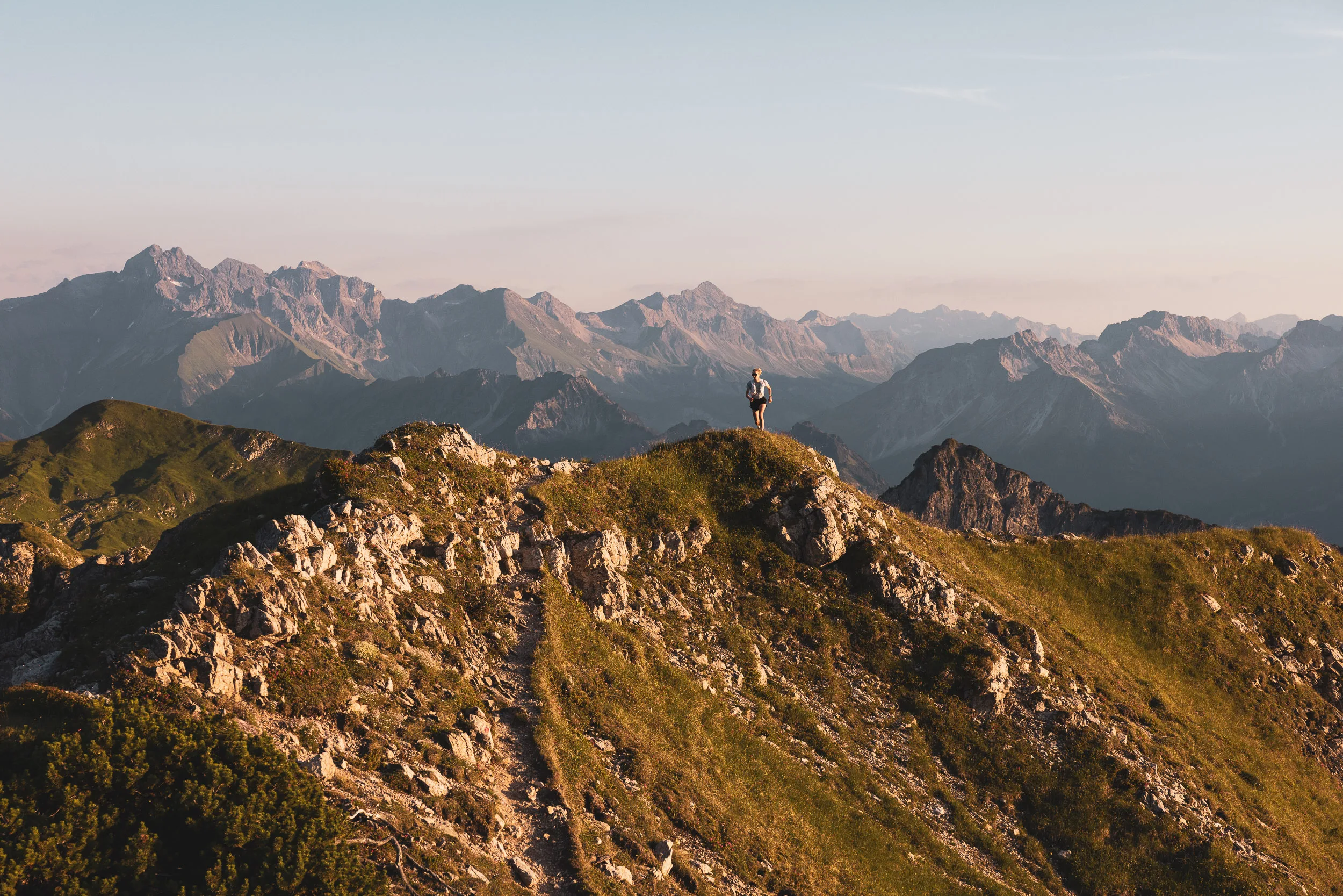 Einzelne Läuferin auf einem Berggrat vor der Weite der Allgäuer Alpen