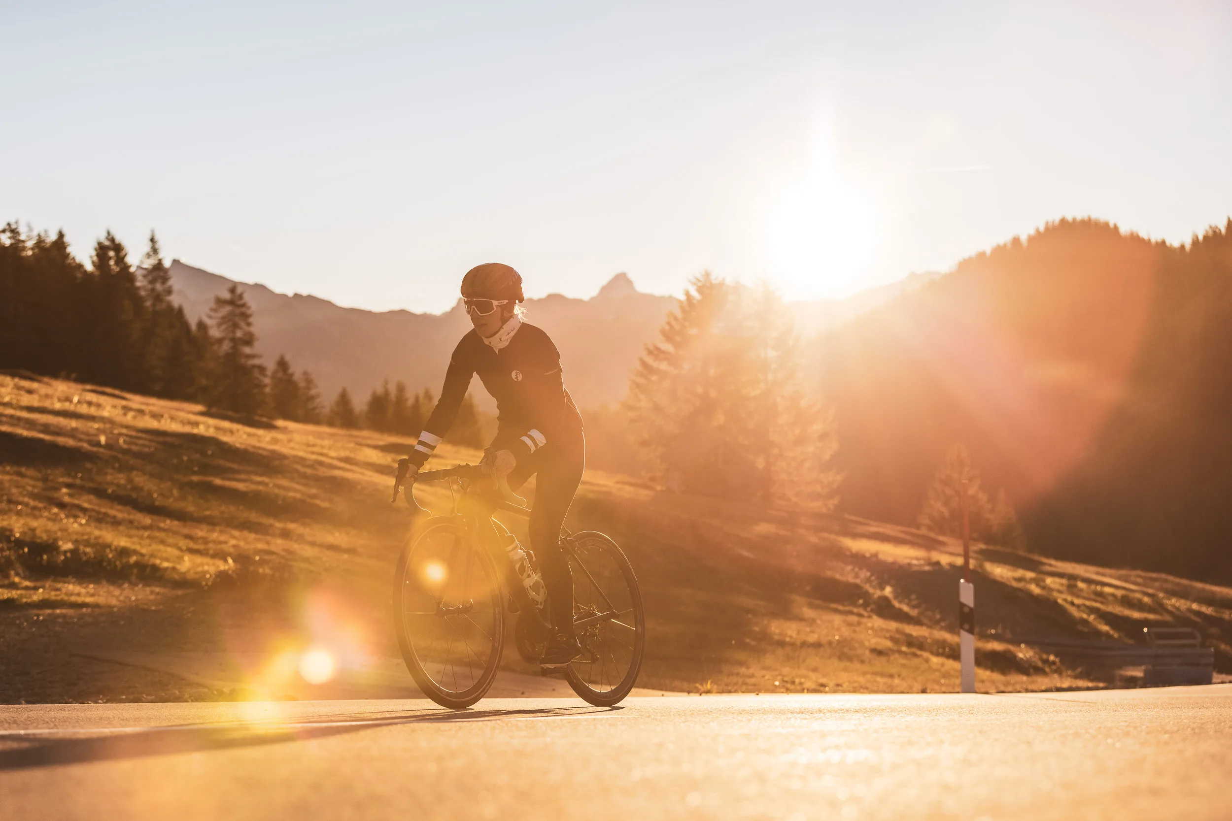 Rennradfahrerin fährt am Abend über die Passstraße im Allgäu