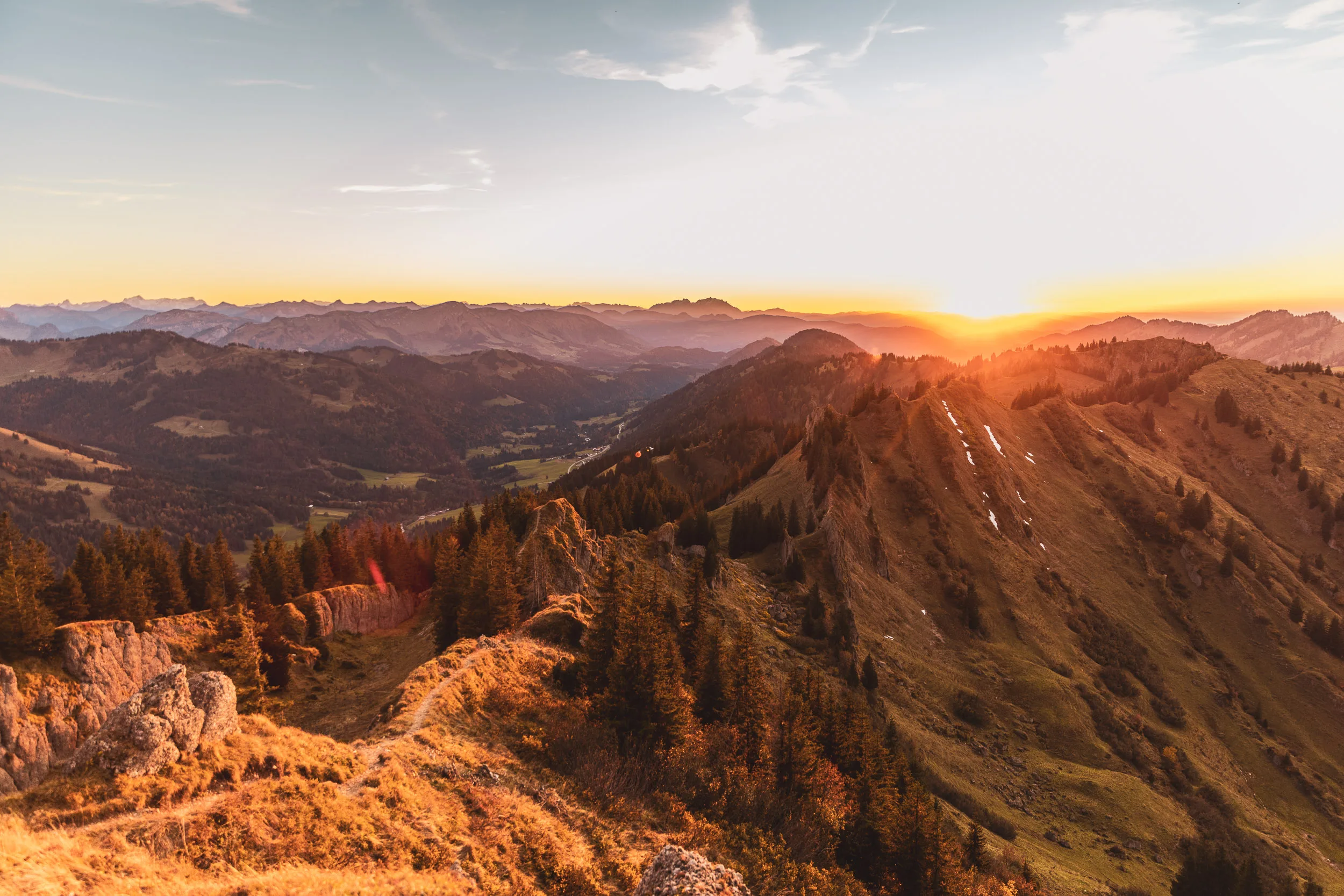 Bergketten und bewaldete Grate leuchten unter der sinkenden Sonne im Oberallgäu