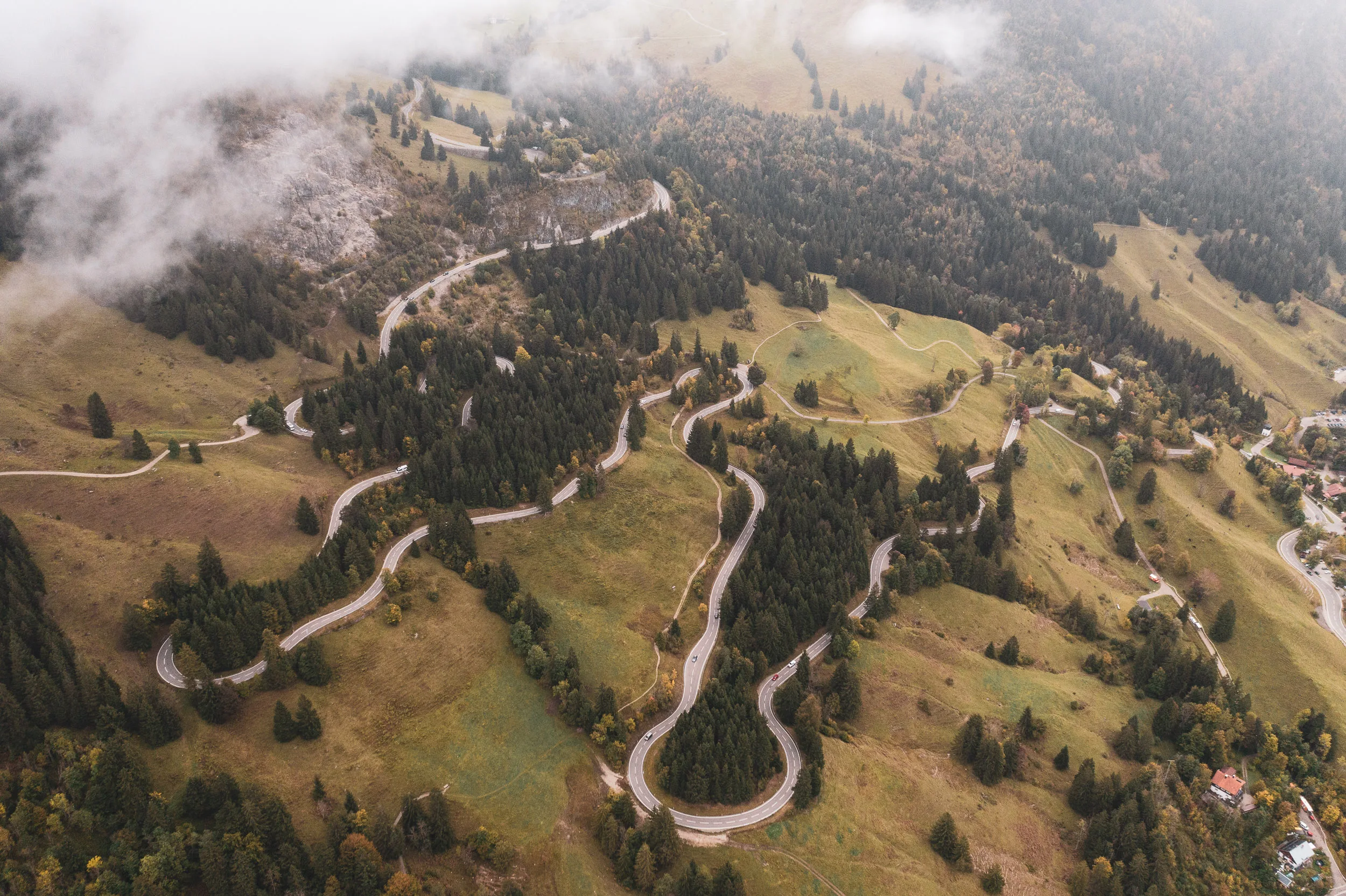 Tiefe Wolken liegen über der kurvigen Passstraße und den herbstlichen Hängen am Oberjoch.