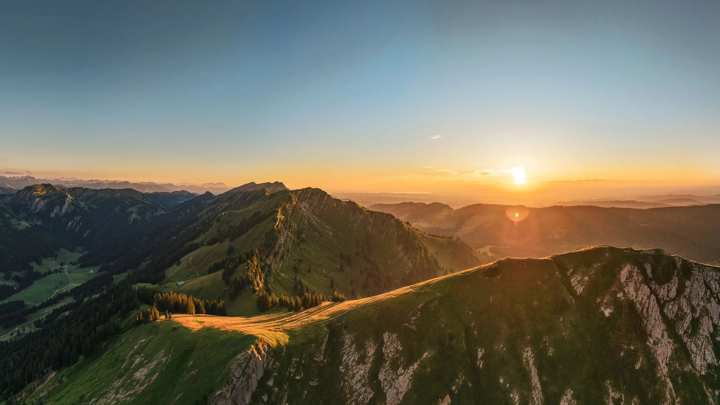 Die untergehende Sonne taucht Grate und Bergwiesen der Nagelfluhkette in warmes Licht.