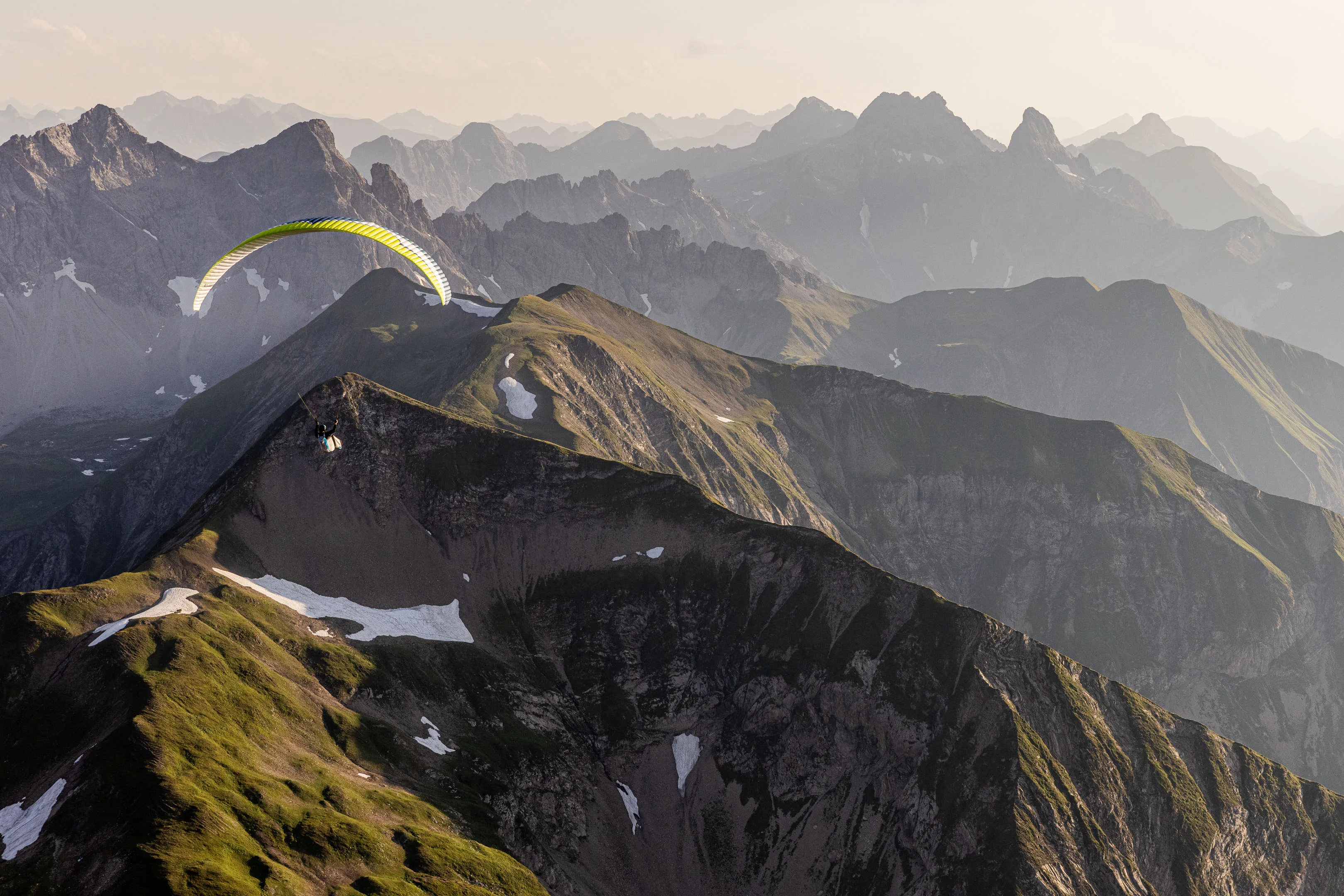 Michael Schnetzer fliegt vor mehreren Bergketten über einen schmalen Rücken