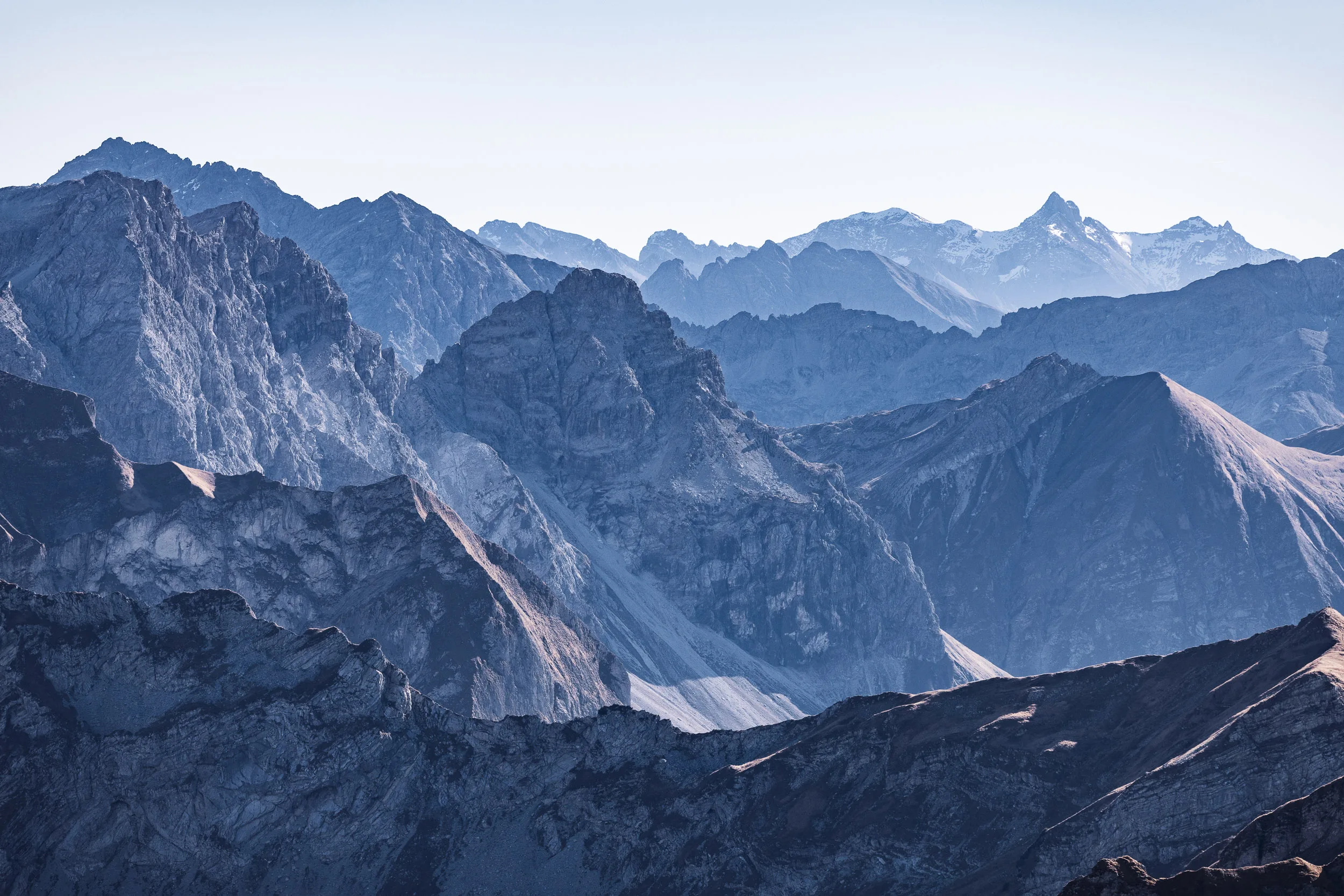 Zahlreiche felsige Bergketten reichen im blauen Dunst bis zum Horizont.