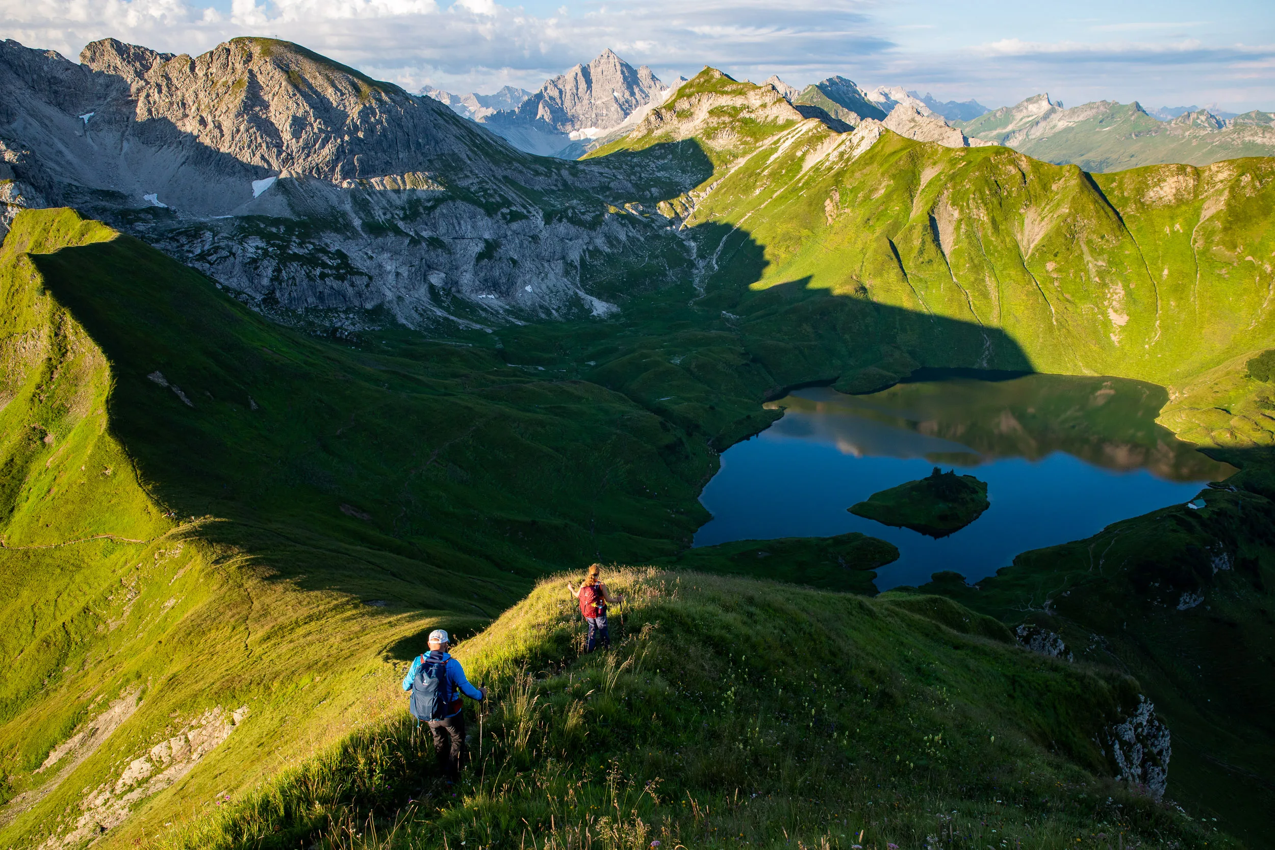 Caroline Nantke und Harald Dreyer steigen über einen Grasgrat mit Blick auf den Schrecksee ab