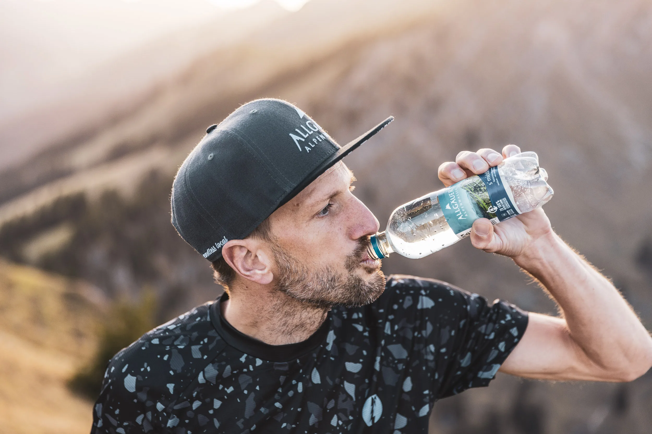 Trailrunner trinkt aus einer Flasche vor der abendlichen Nagelfluhkette