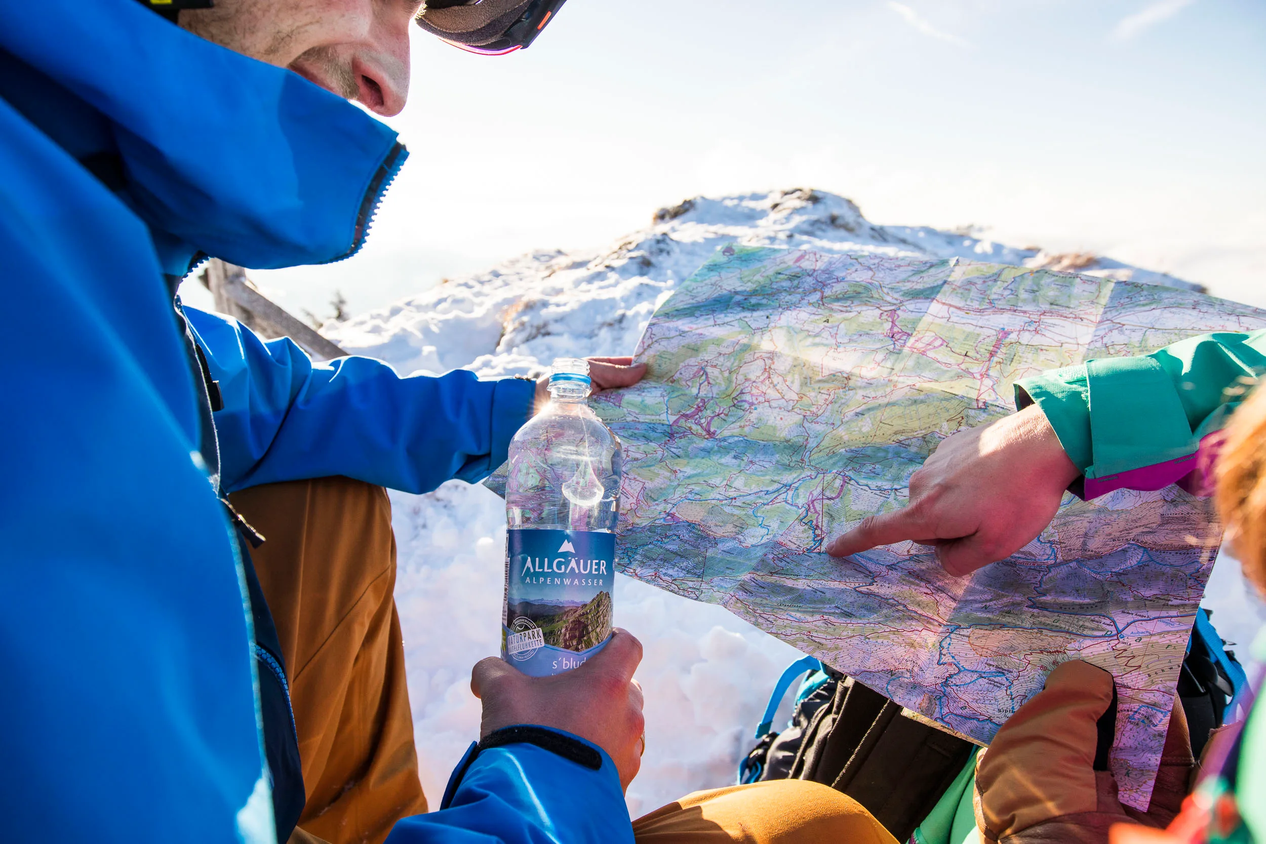 Skitourengeher planen ihre Route über einer Karte im Schnee.