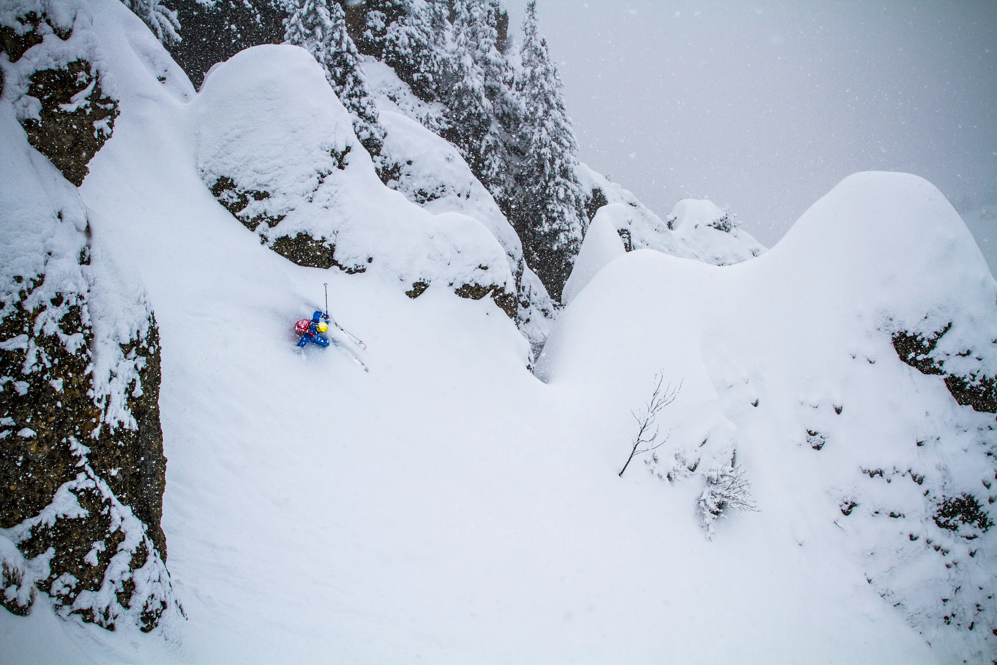 Freerider fährt durch eine enge Schneerinne zwischen schneebedeckten Felsen
